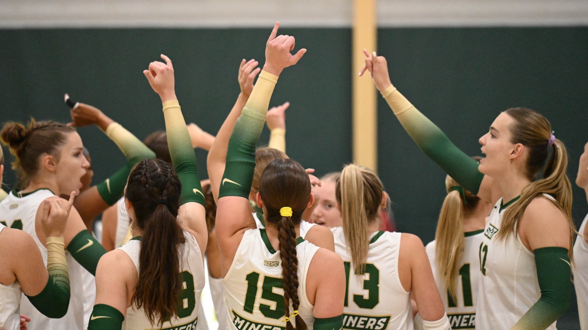Women's Volleyball Team Photographed breaking a huddle with their hands in the air while wearing white uniforms before a match at the MSSU Tournament