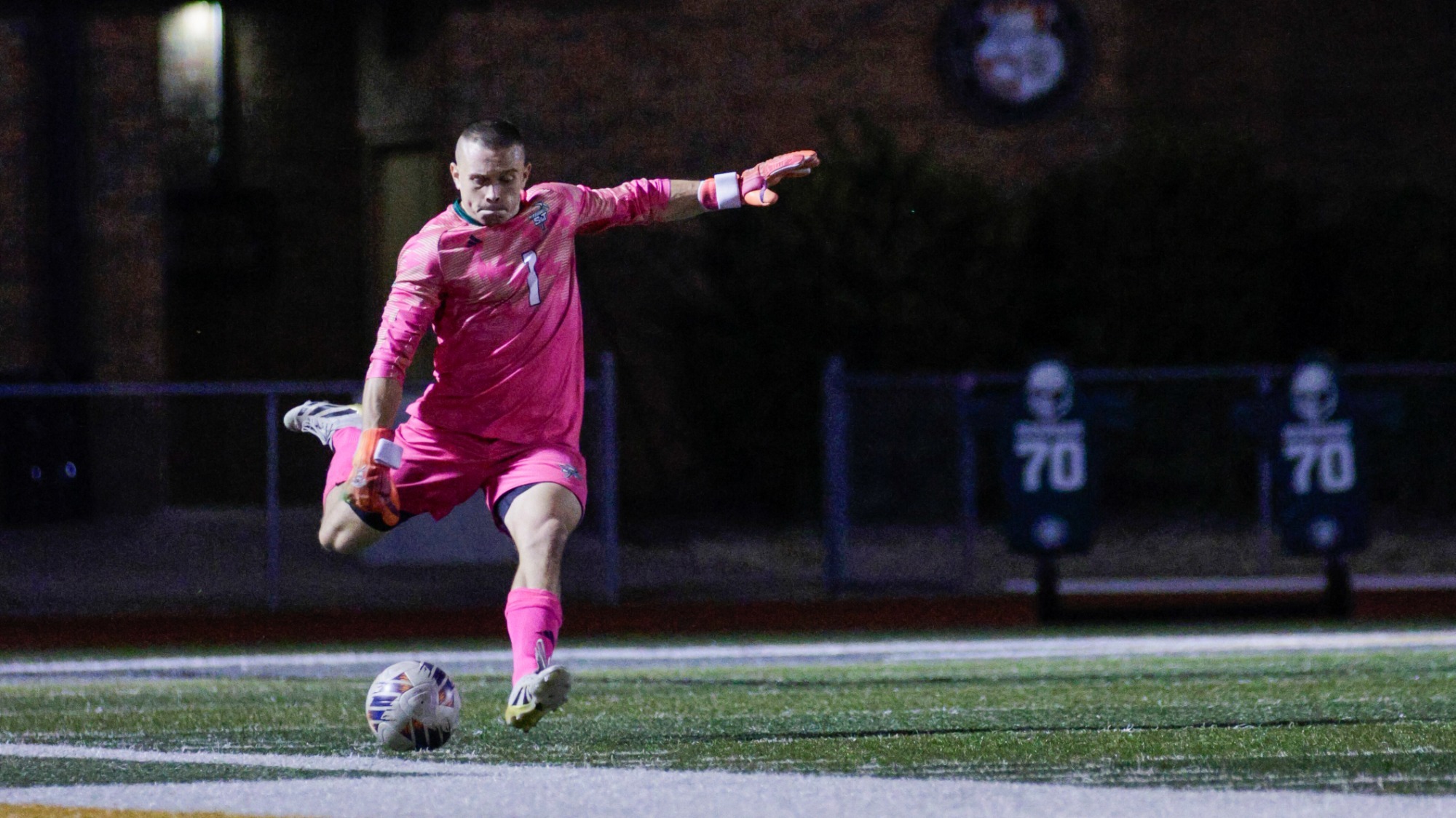S&T Goaltender Cavitt Bruhn in a pink jersey and pink shorts punting the soccer ball 