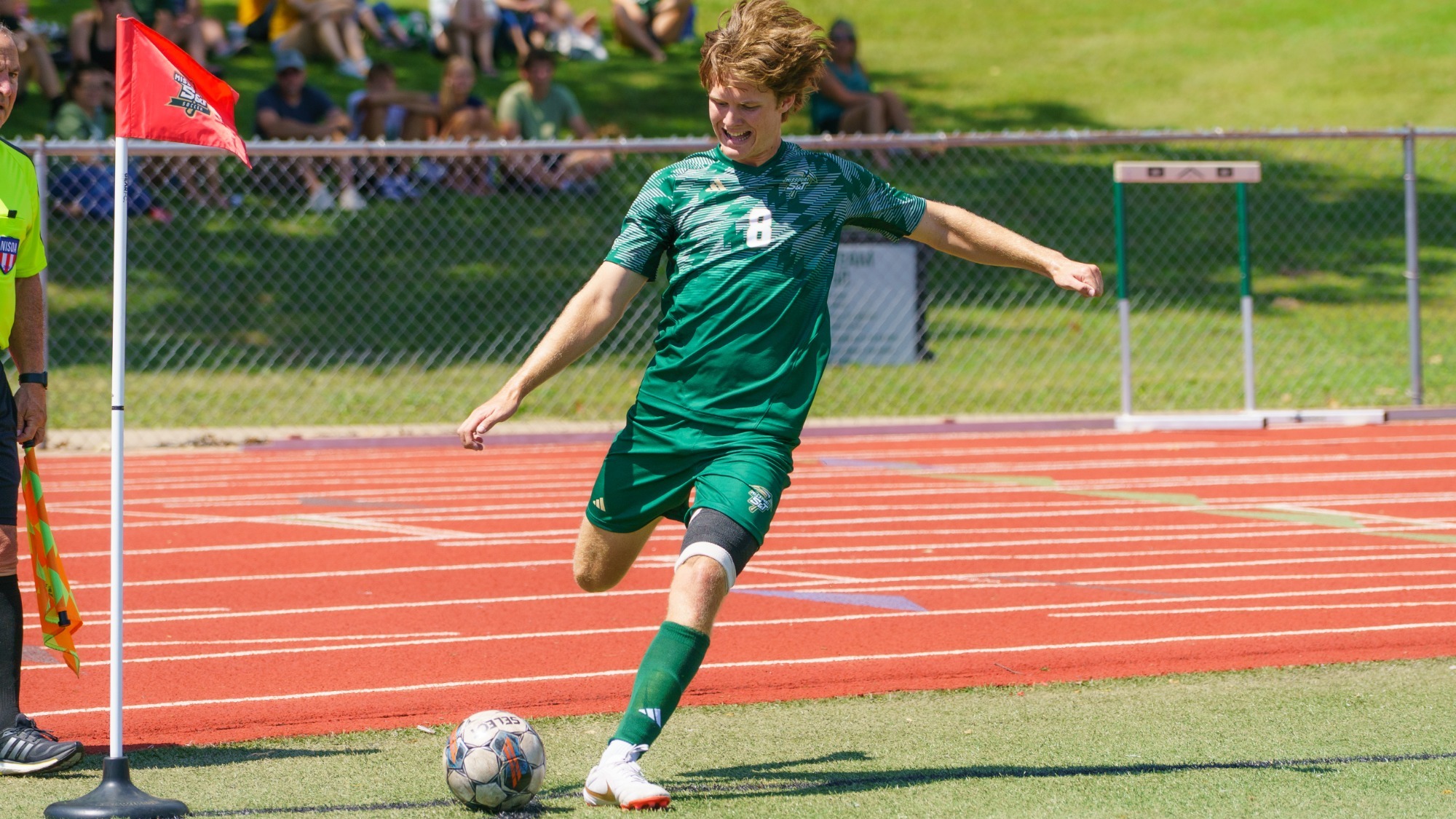 Luke Giesing of Missouri S&T Men's Soccer photographed mid-kick while taking a corner kick. He is wearing a green uniform.