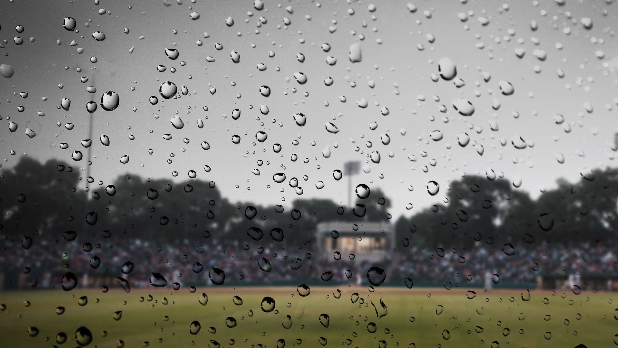A rain-stained screen in the foreground with a blurry baseball field in the background