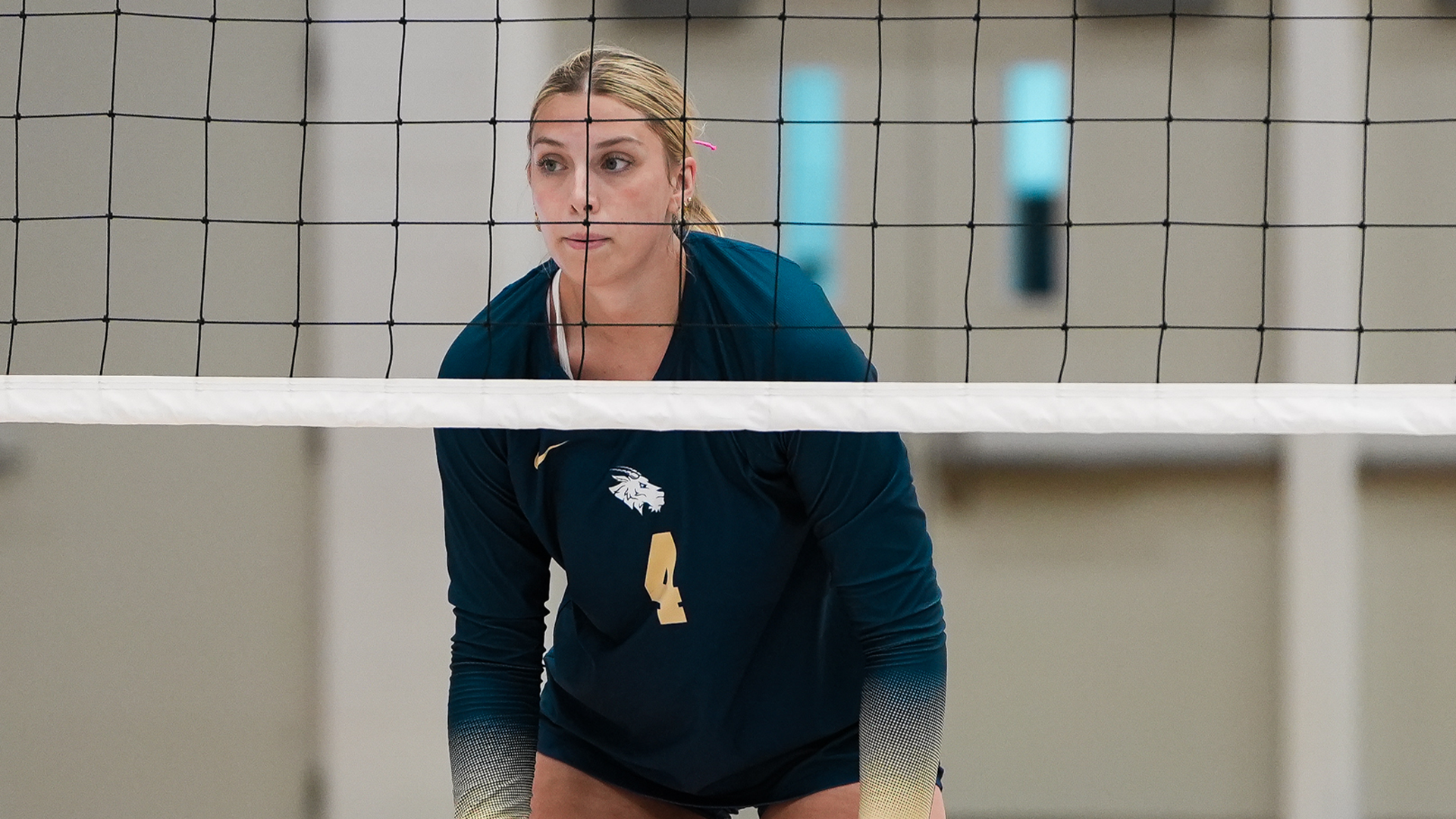 Kaylen Lembcke standing behind a volleyball net