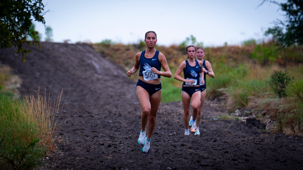 Adriana Rodriguez and teammates run down a muddy hill