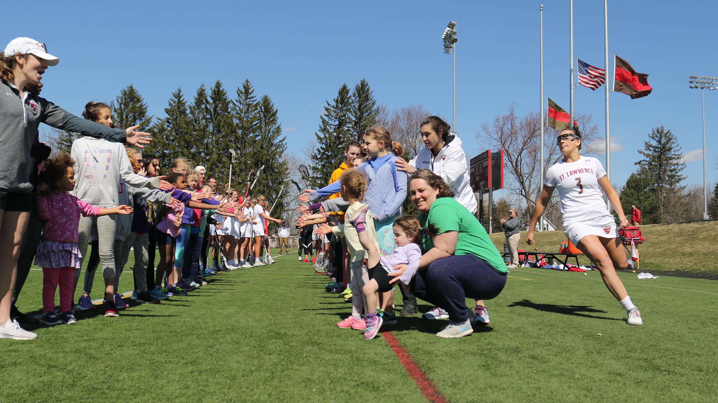 Participants line up to give women's lacrosse starters high fives as they ran out onto the field for their game against Bard