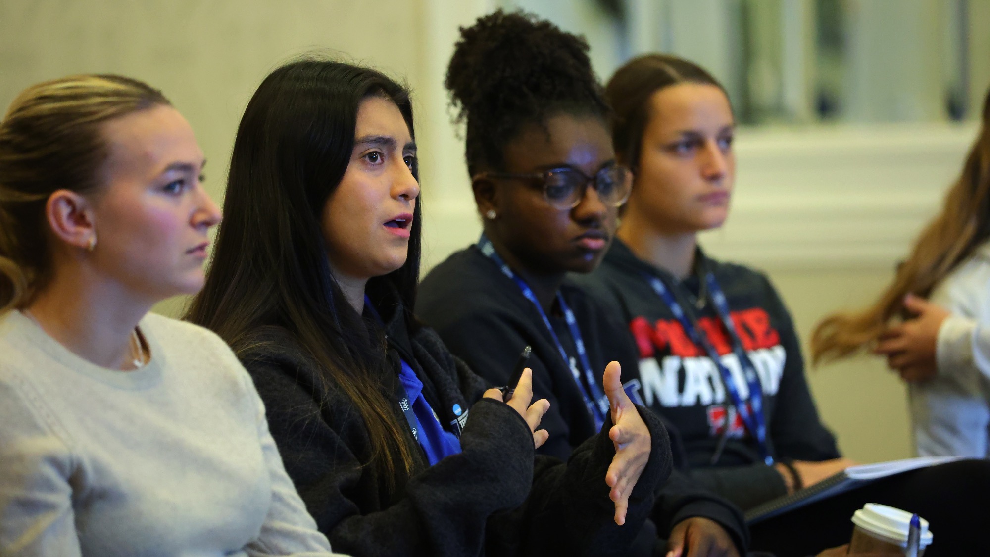 Stela Sifuentes sits in a circle at the NCAA Leadership Forum and explains her point using her hands.