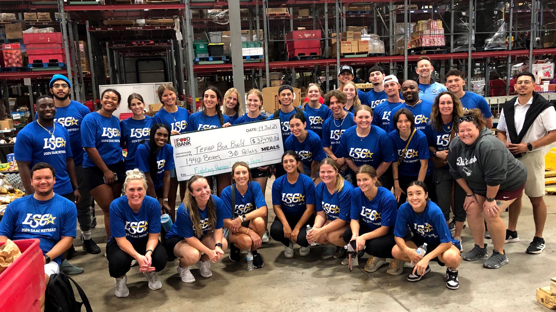 The delegates from each school pose with the large check at the San Antonio Food Bank.