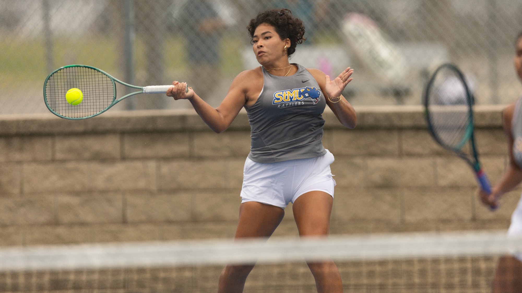 Gia Posito smashes a one-handed forehand on the baseline during doubles play at the Brother Al Invitational