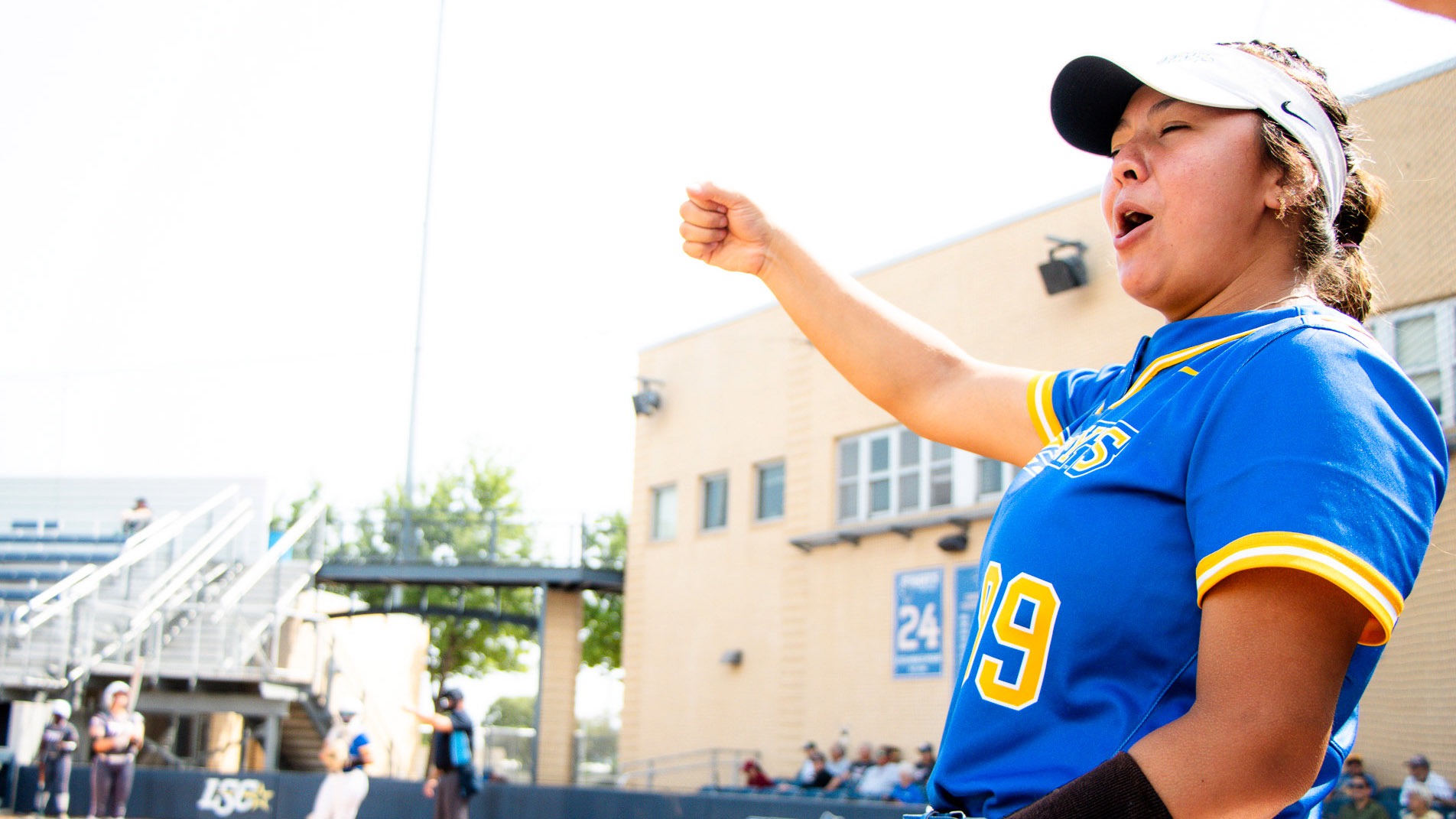 Emily Ayala celebrates in the dugout with her fist raised overhead.