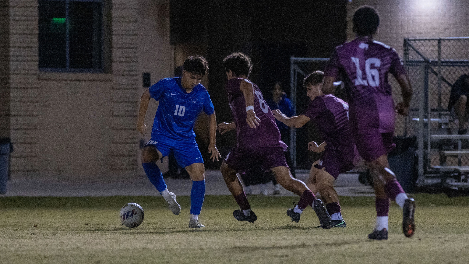 Kai Louviere taps the ball with his right foot as three WT defenders close around him.