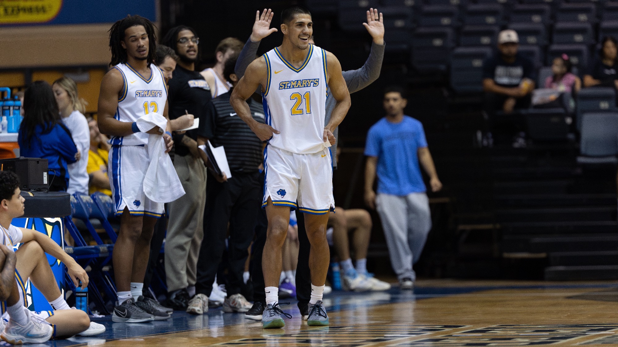 Sebastian Mendoza smiles while holding his hands on his hips in front of the Rattlers bench.