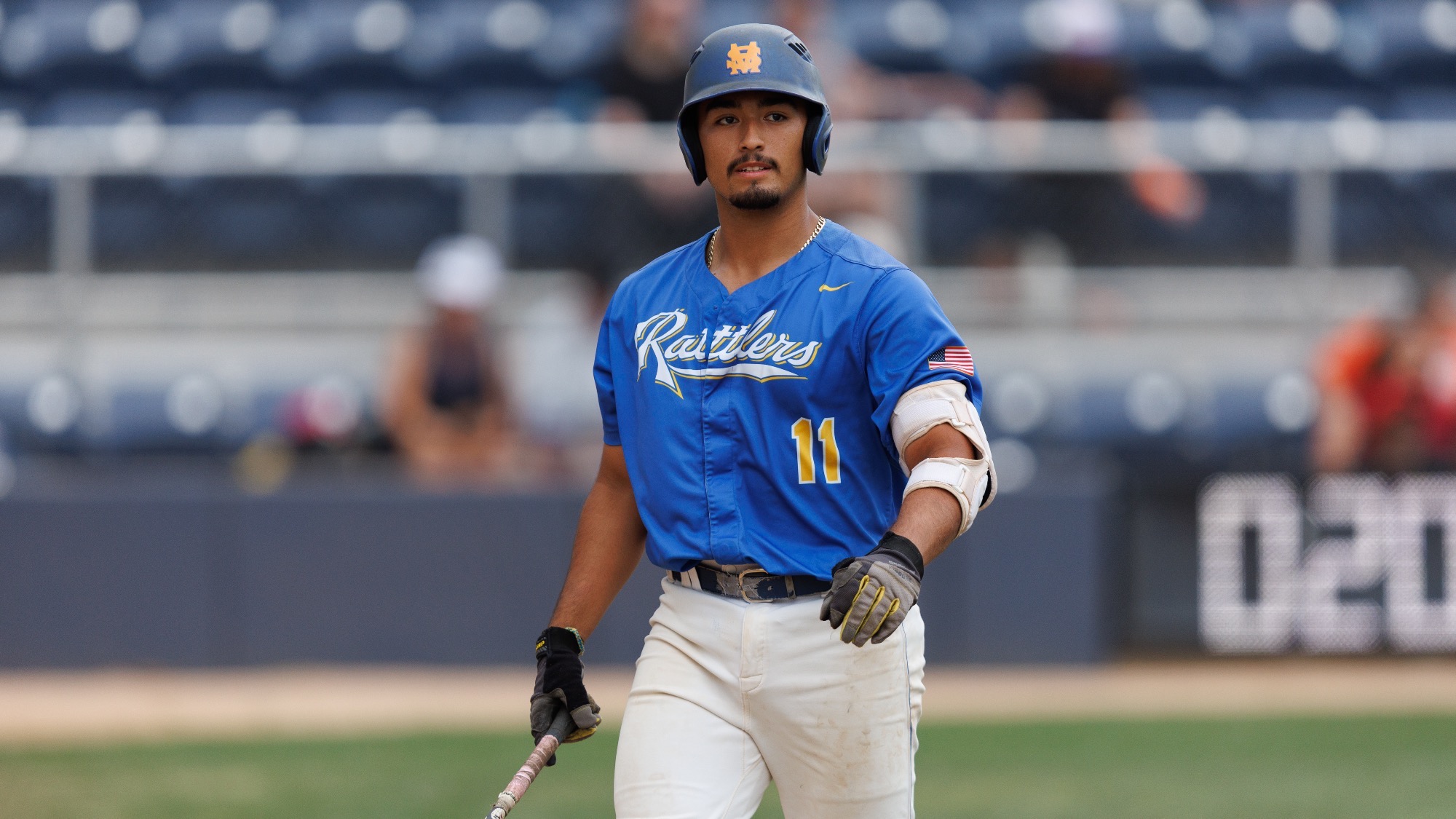 Dillon Lopez walks with bat in right hand and batting helmet on.