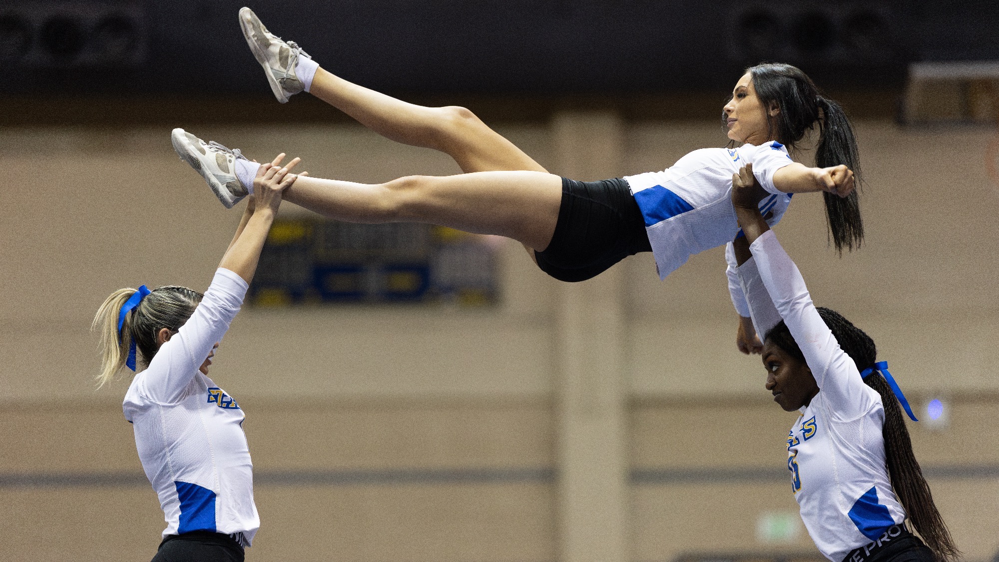 Tiffany Gomez, left, and Sydnye Forde-Richins lift Yanelle Nicholson over their heads at the top of a lift.