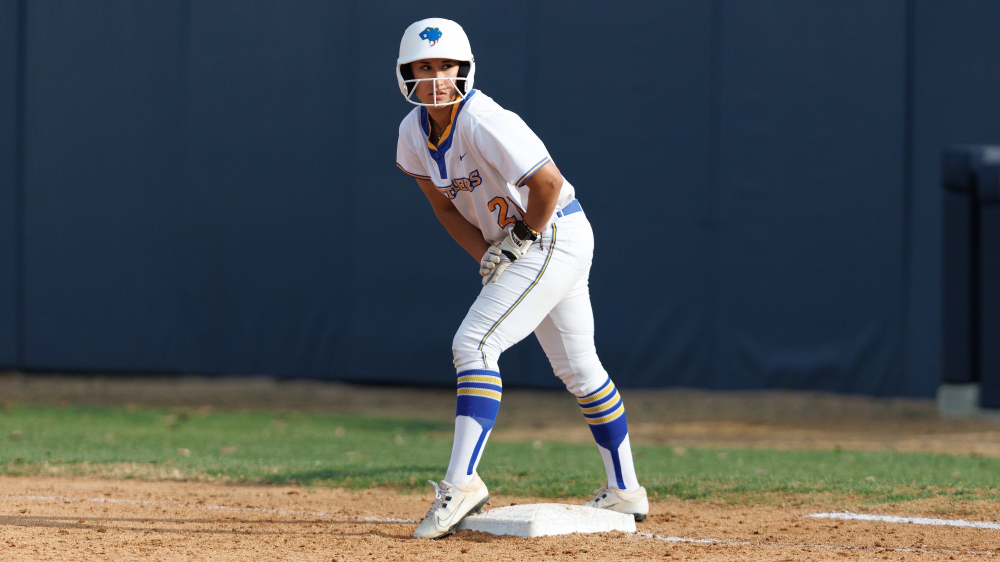 Iliana Melendez stands on first base with left leg cocked, ready to run.