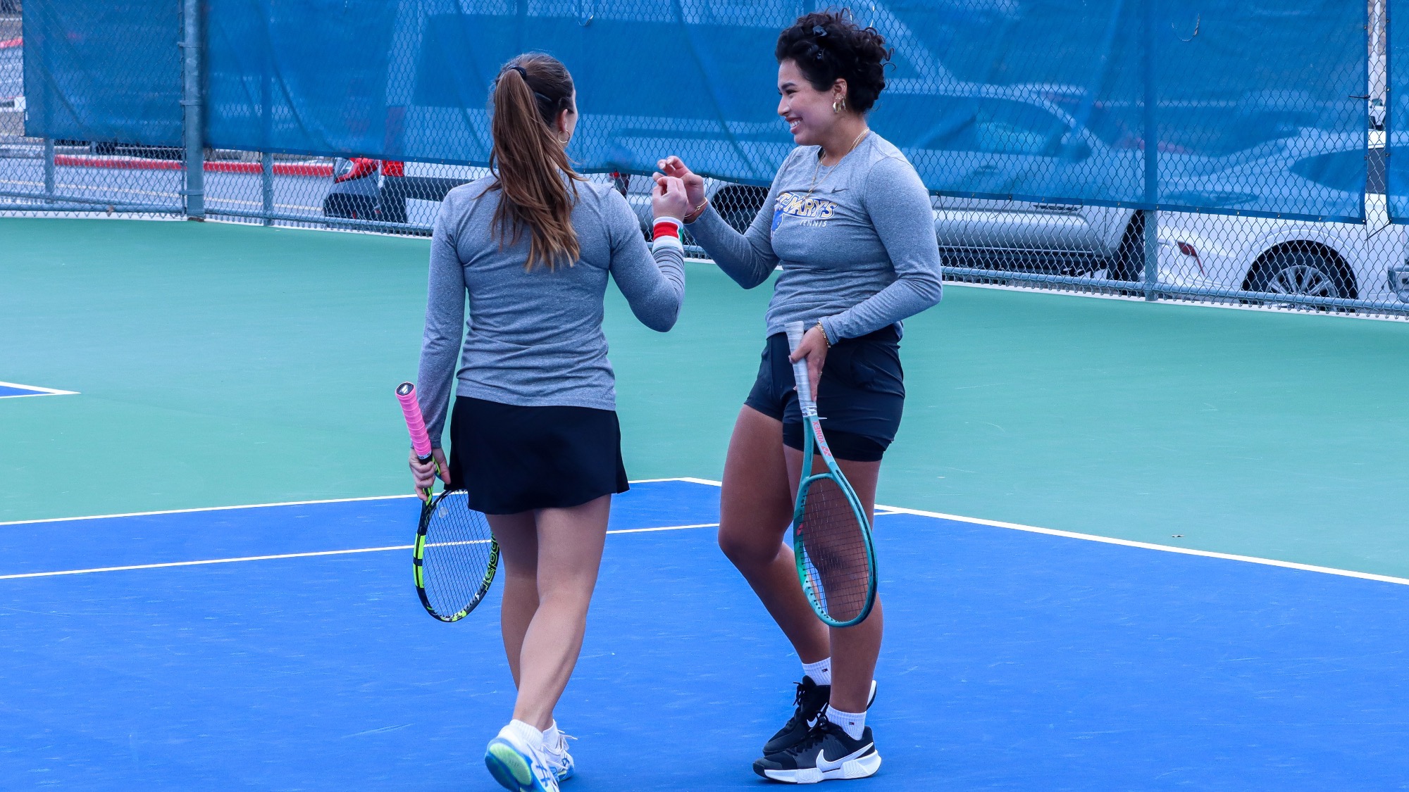 Alessia Terlizzi and Gia Posito smile and slap hands after winning another doubles point.