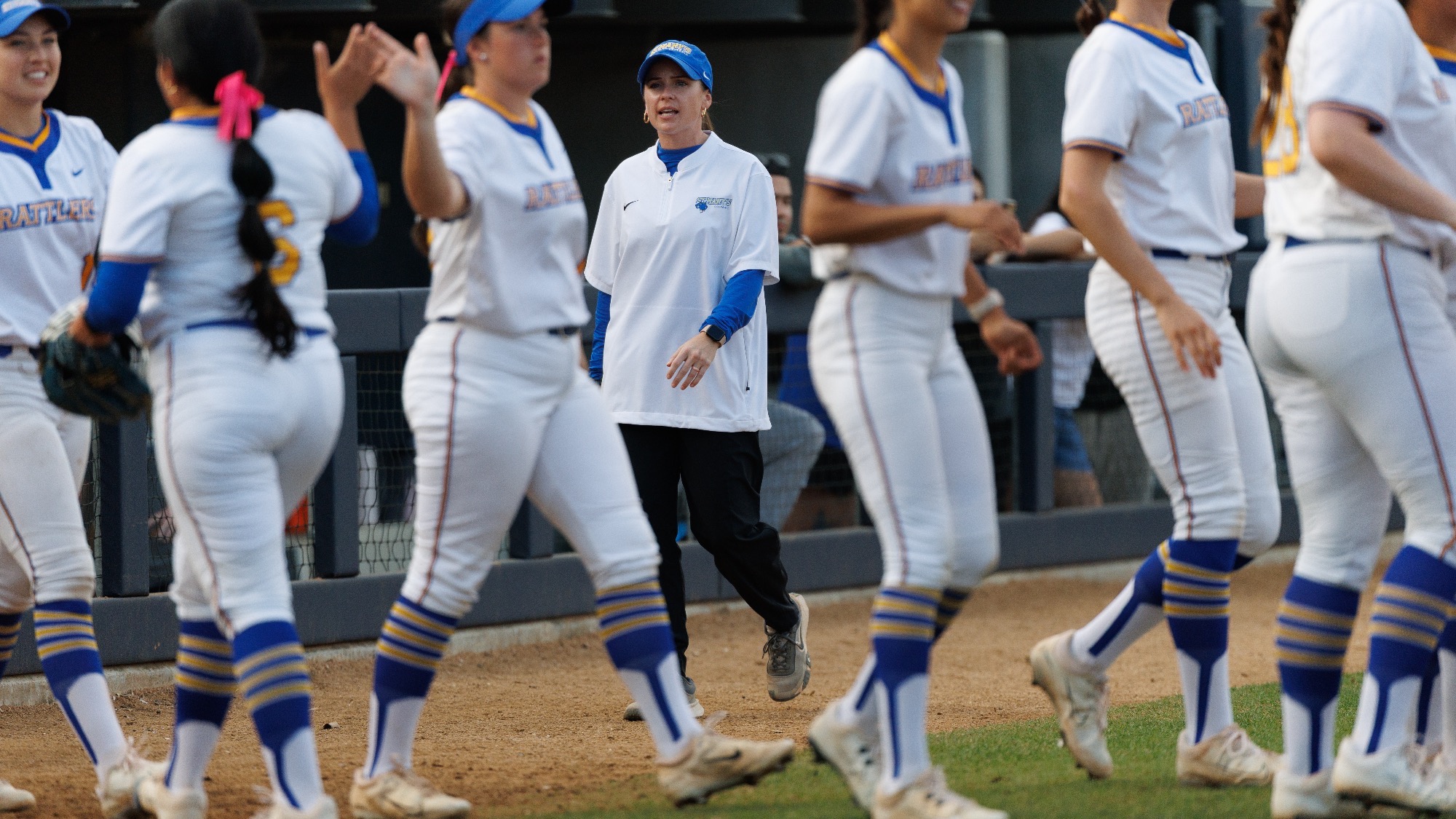 Taylor Lira stands behind her players as they give each other high fives.