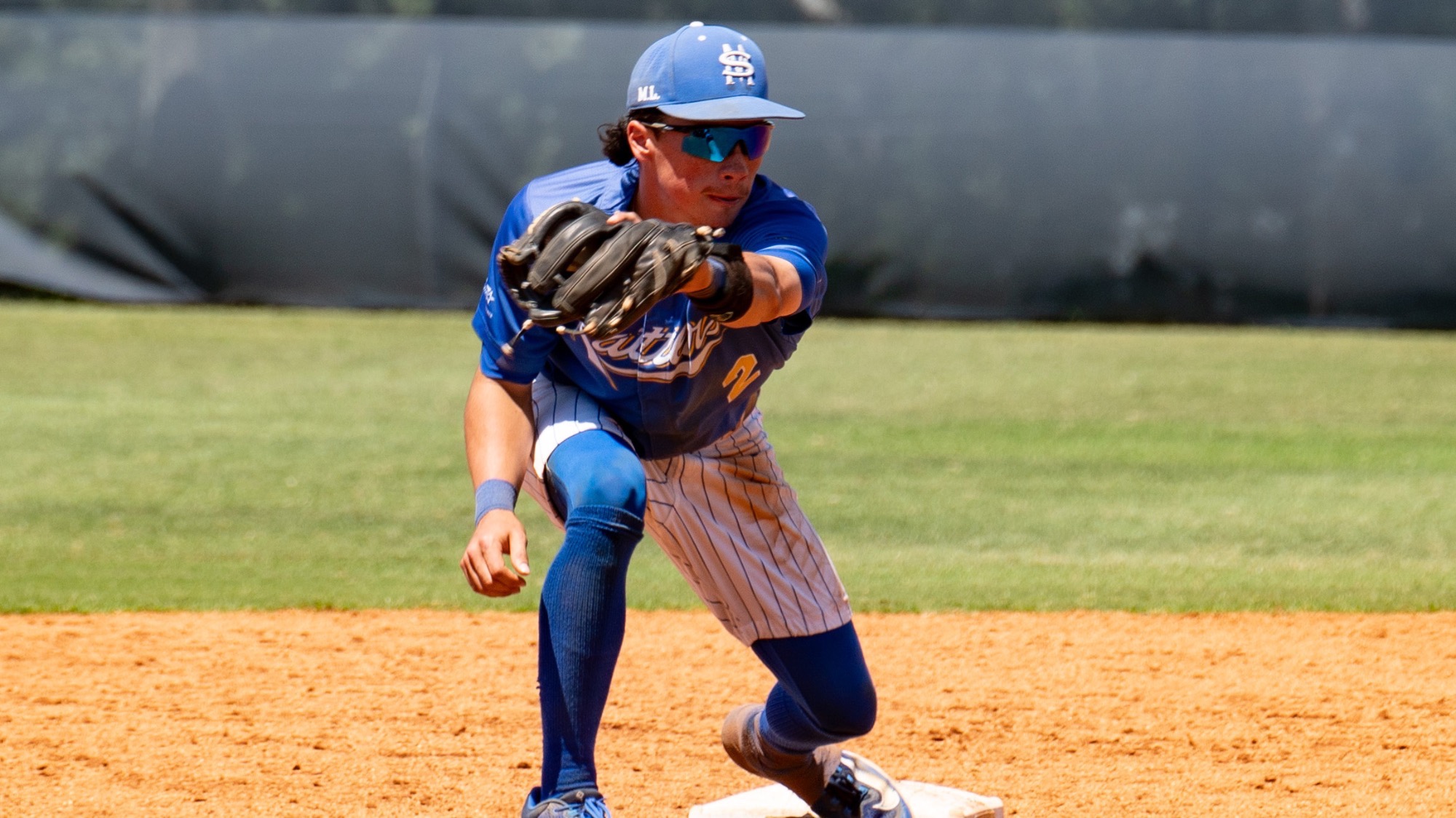 Raithen Malone squats down at second base to catch the ball and apply the swipe tag.