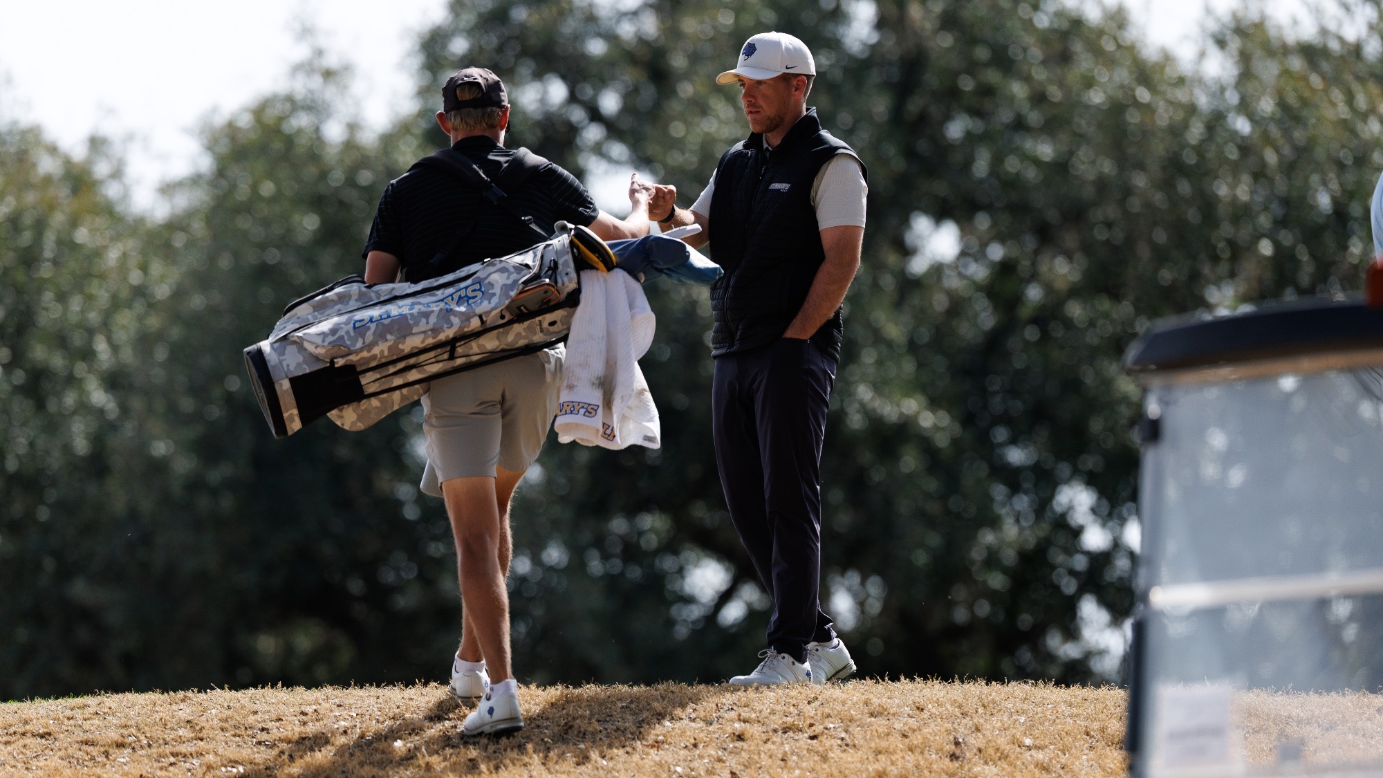 Coach McCarthy stands on a ridge, fist bumping Philip Hallstrom as he climbs the hill.