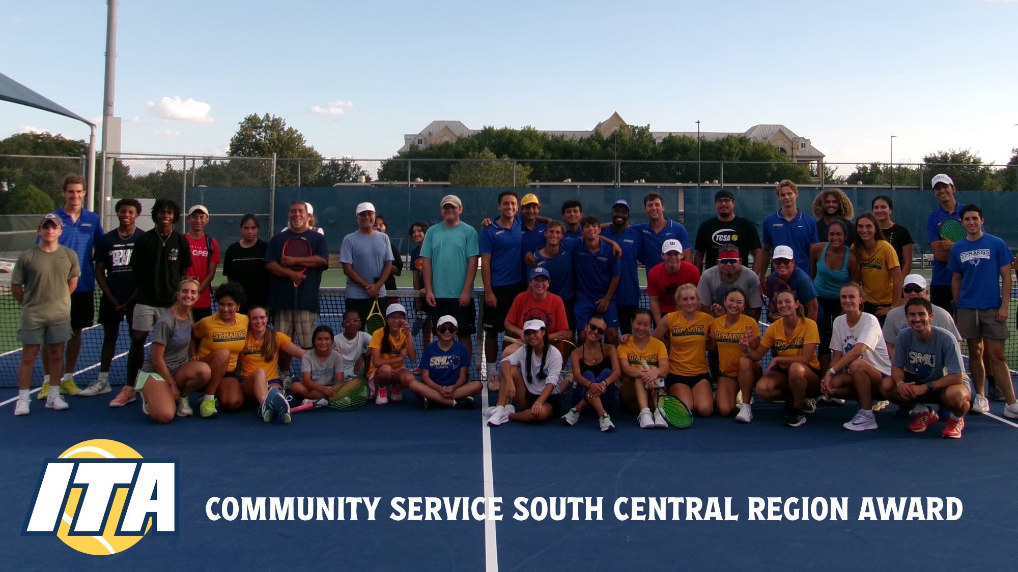 The Men's and Women's Tennis team poses in front of the net with attendees at a free clinic.