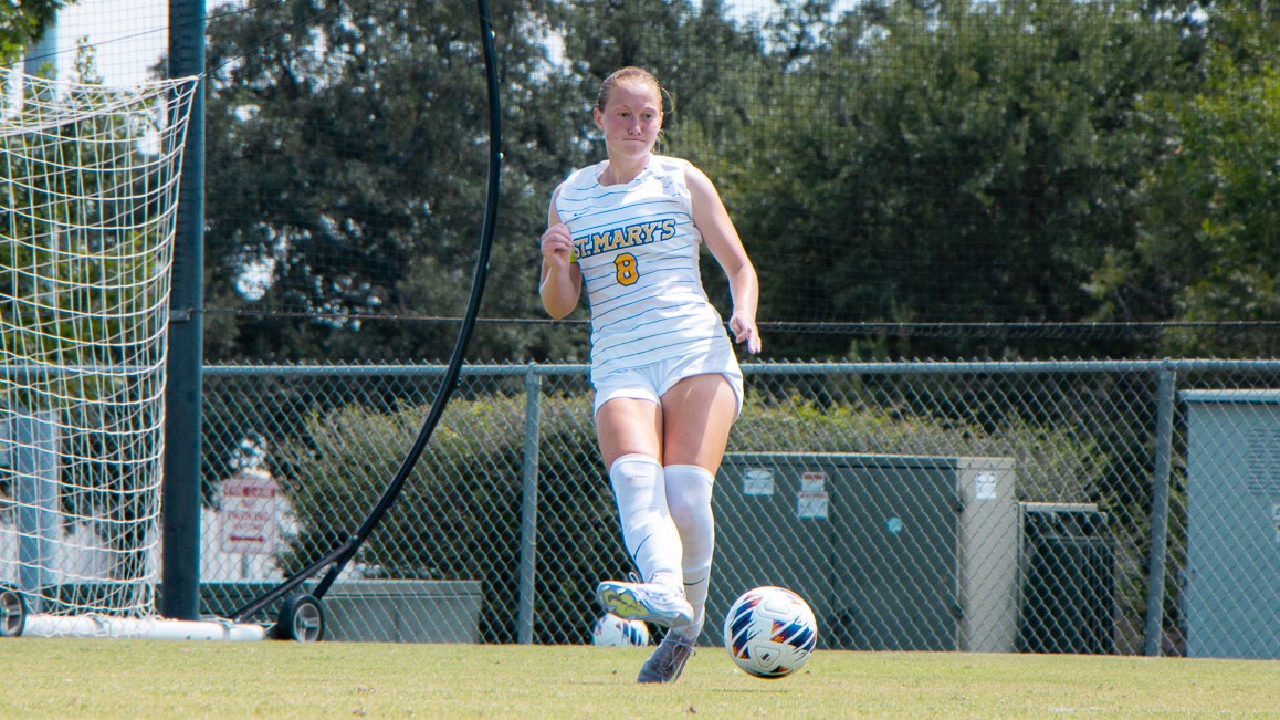 Valerie Hover passes the soccer ball to her left with her right foot.
