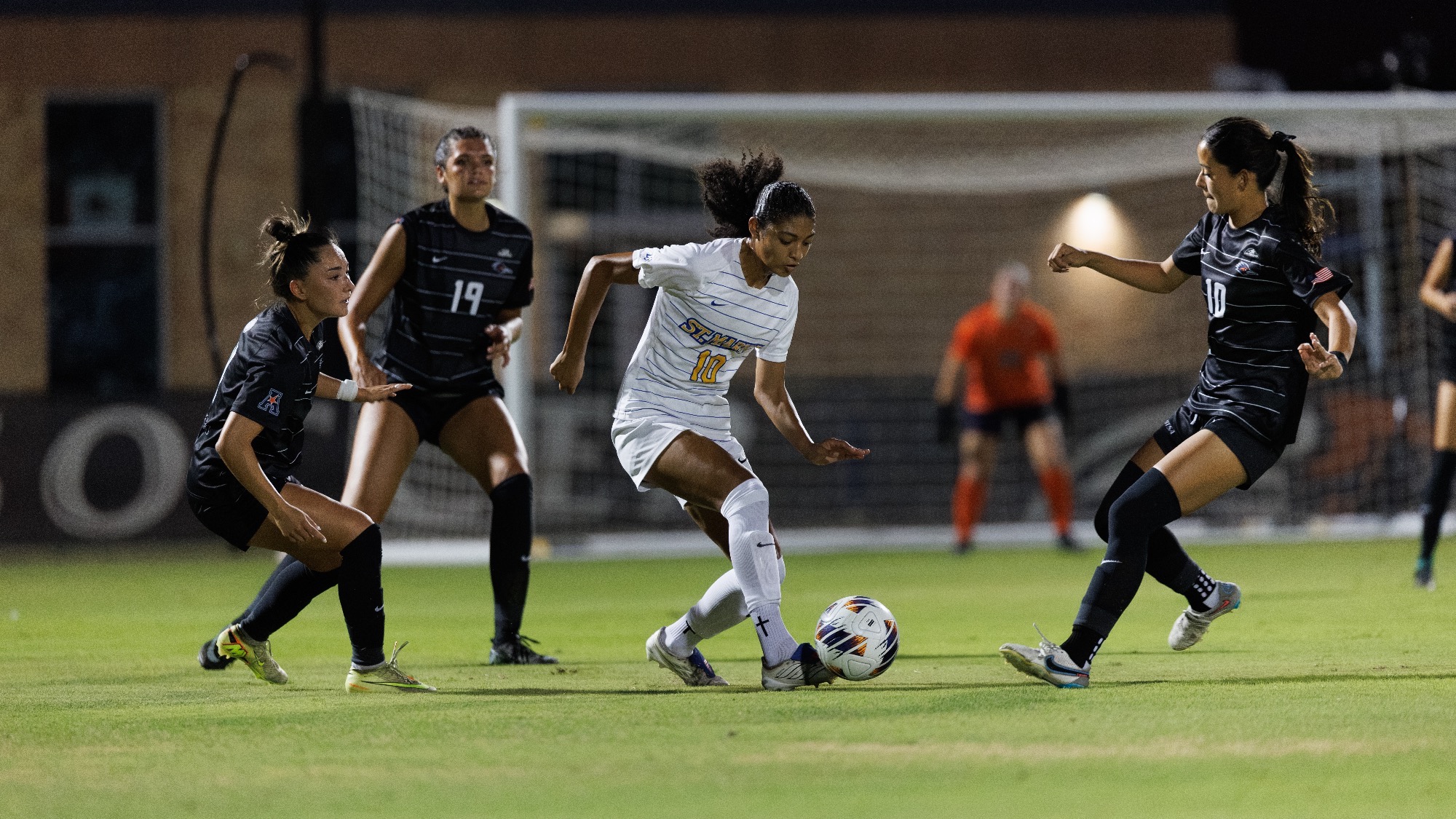 Kamrynn Martinez dribbles with her left foot with three UTSA defenders around her.
