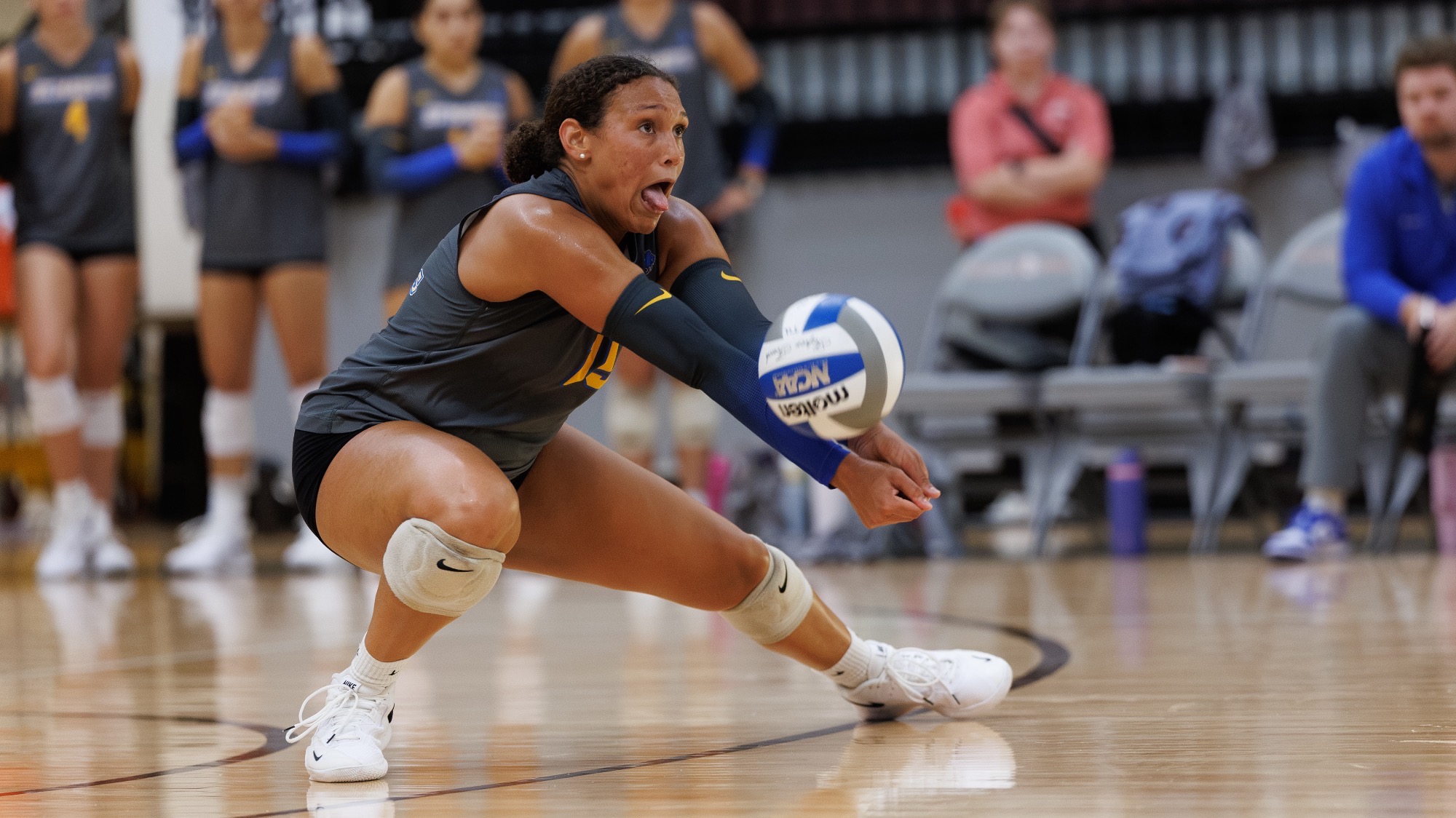 Taylor Alston sticks her tongue out as she digs a ball at Trinity.