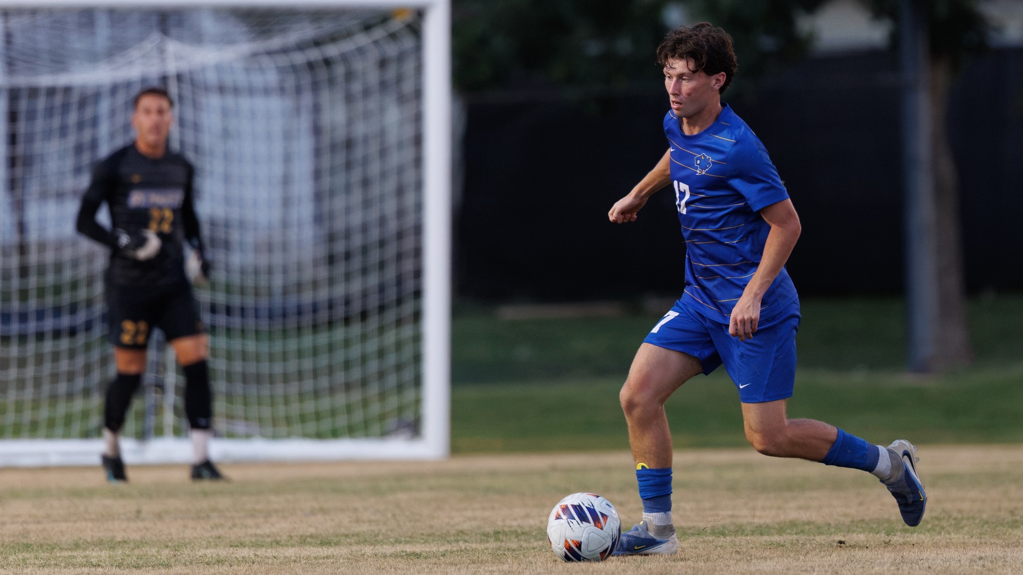 Sean Borland moves to the left with the ball with GK Nichita Misac blurry in the background.