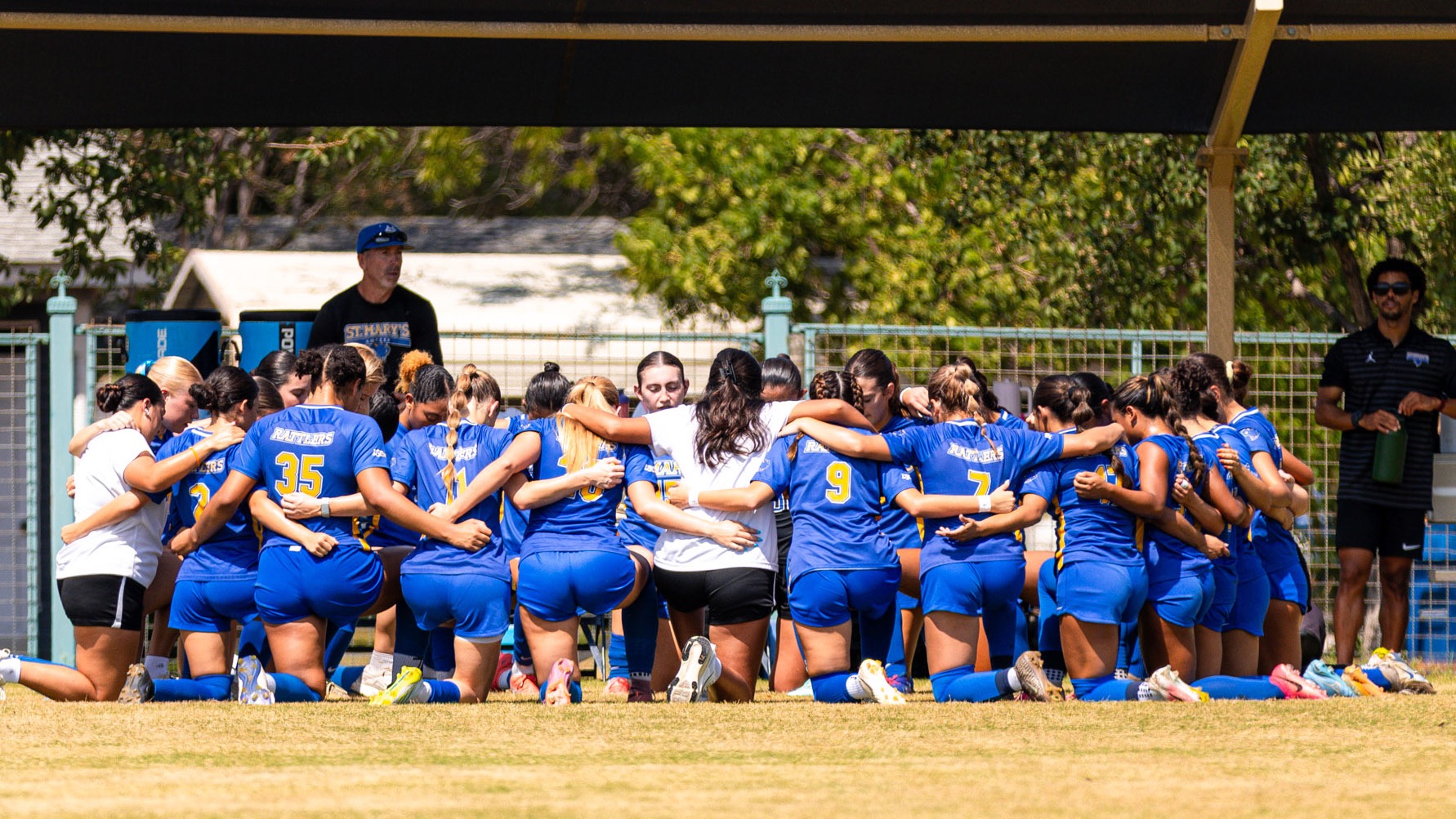 The women's soccer team huddles on one knee as they say a prayer before kicking off against Lynn.