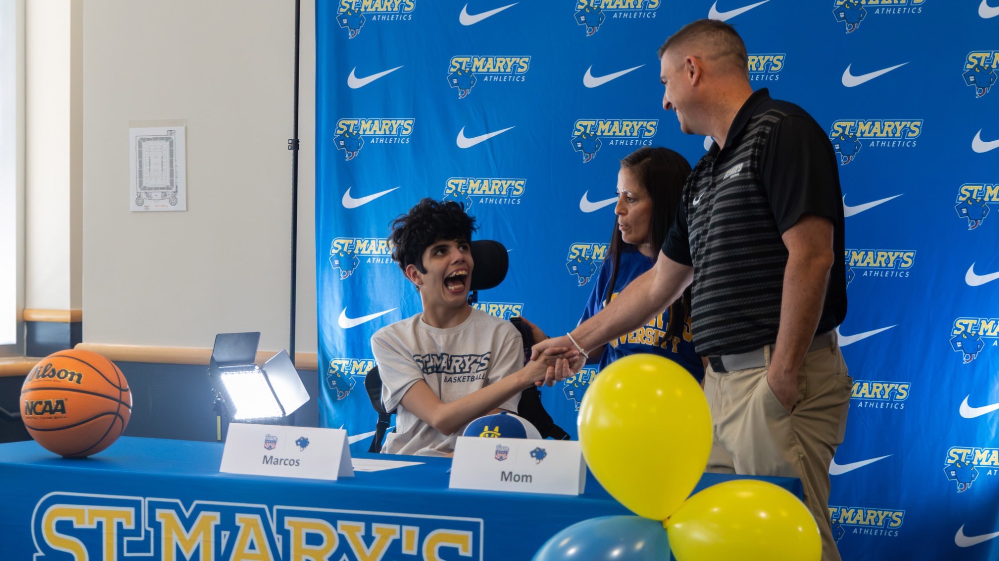 Marcos on the left, his mom in the middle and Coach Meyer shaking hands with Marcos after the Team IMPACT signing.