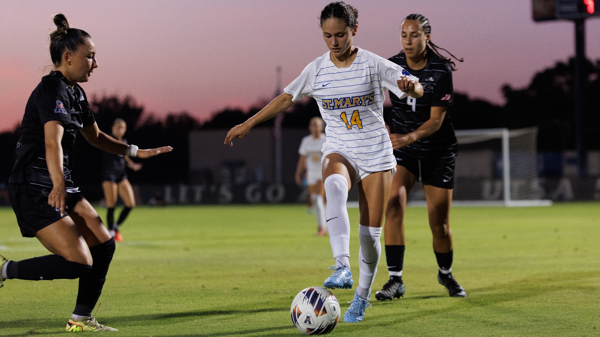 Emilee Durante dribbles with her right foot with two UTSA defenders surrounding her.