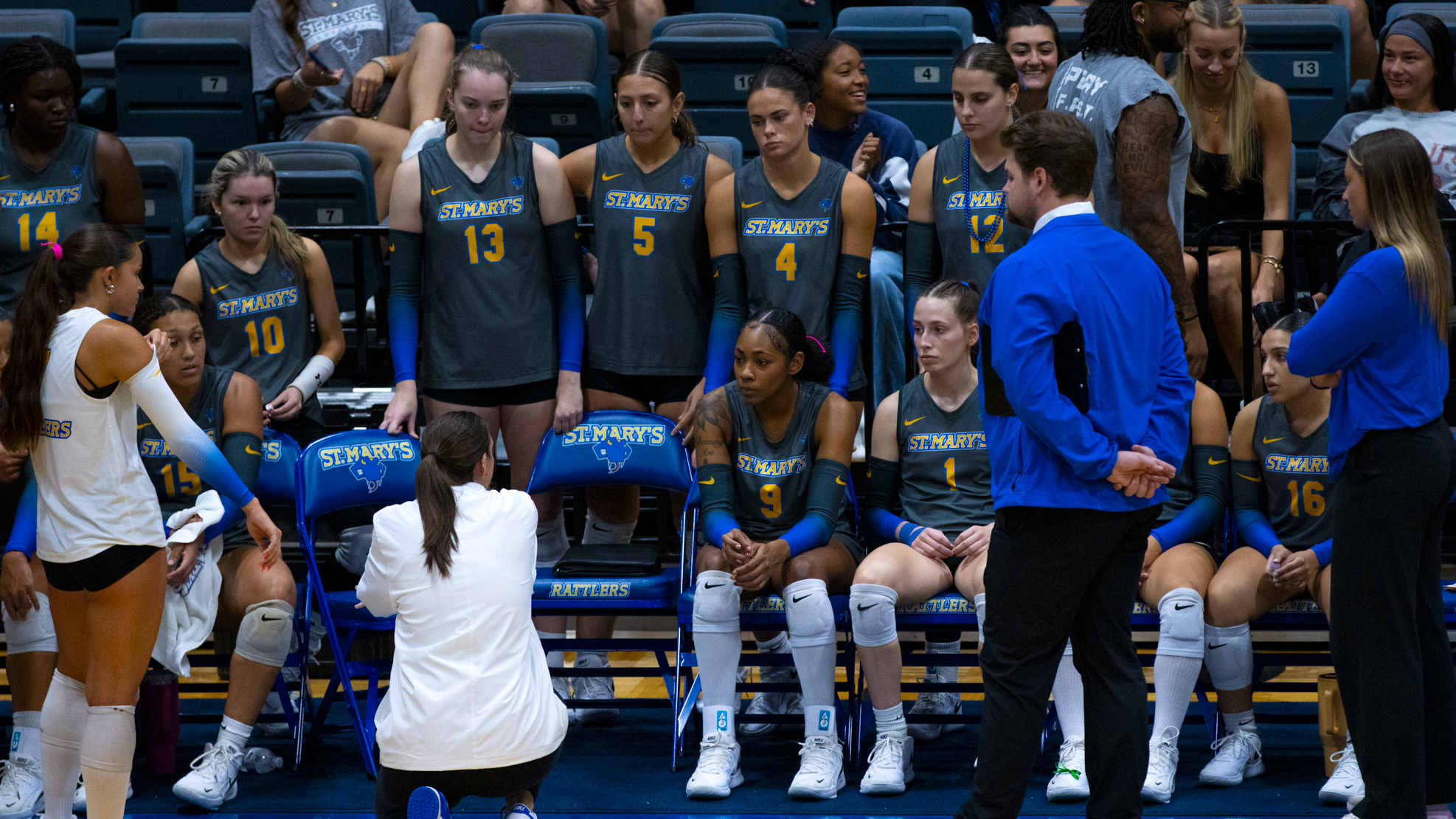Head Coach Kristine Pelky squats down in front of the team during a timeout.