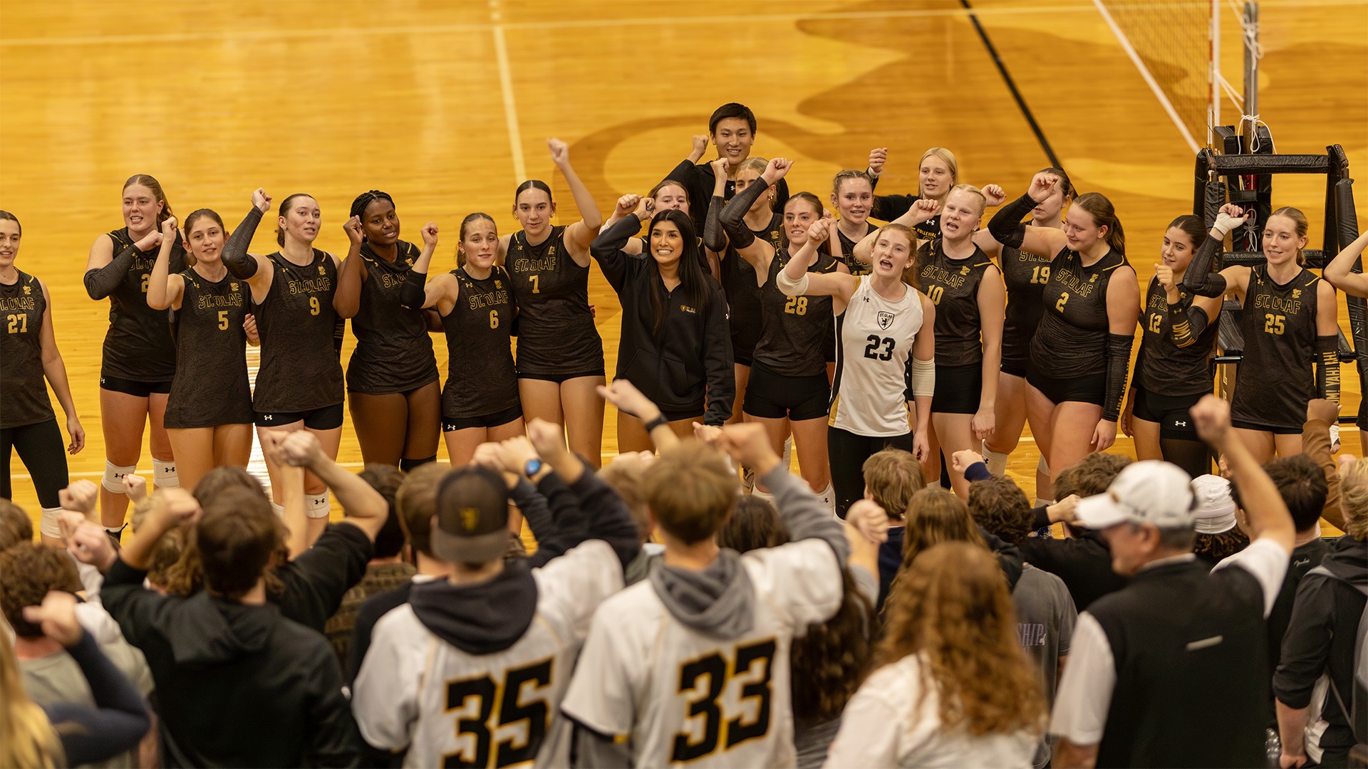 The St. Olaf volleyball team sings Um! Yah! Yah! in front of the student section.