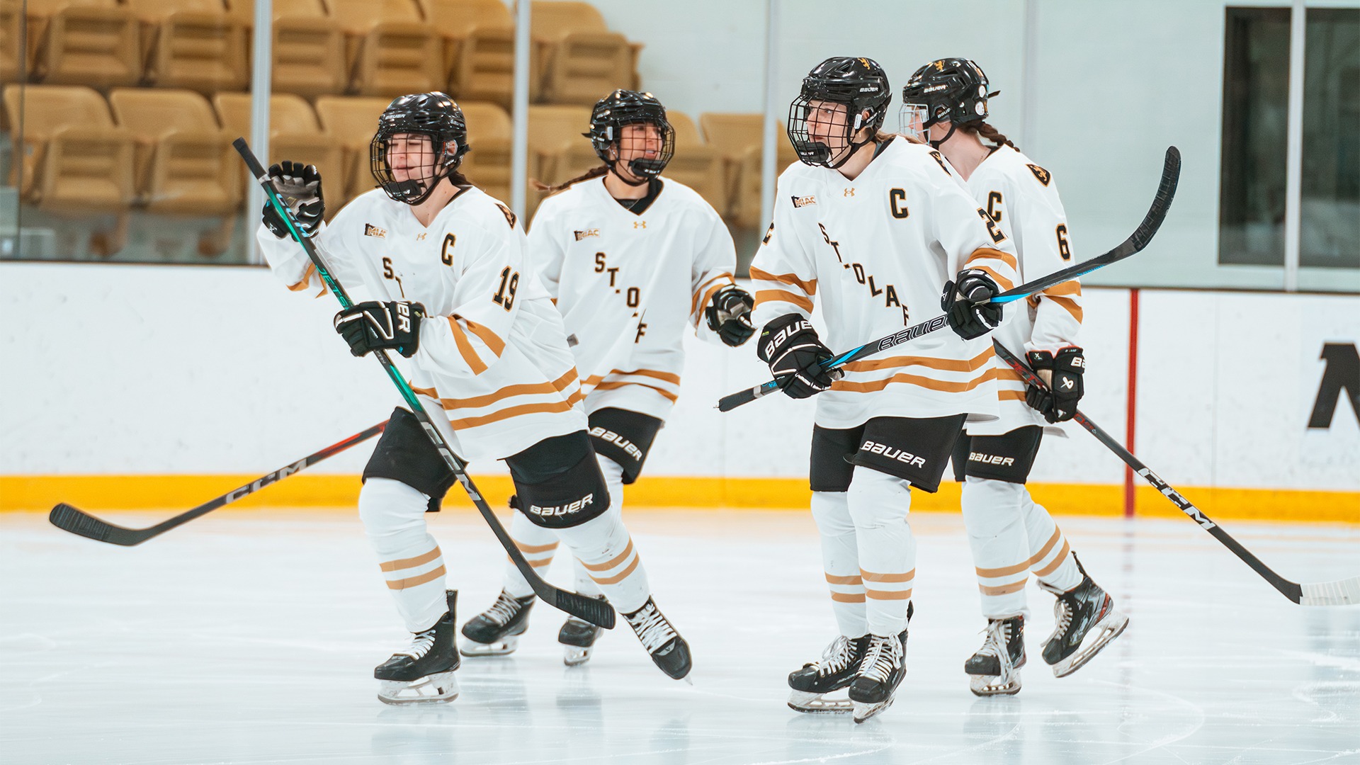 Women's hockey players celebrate a goal.