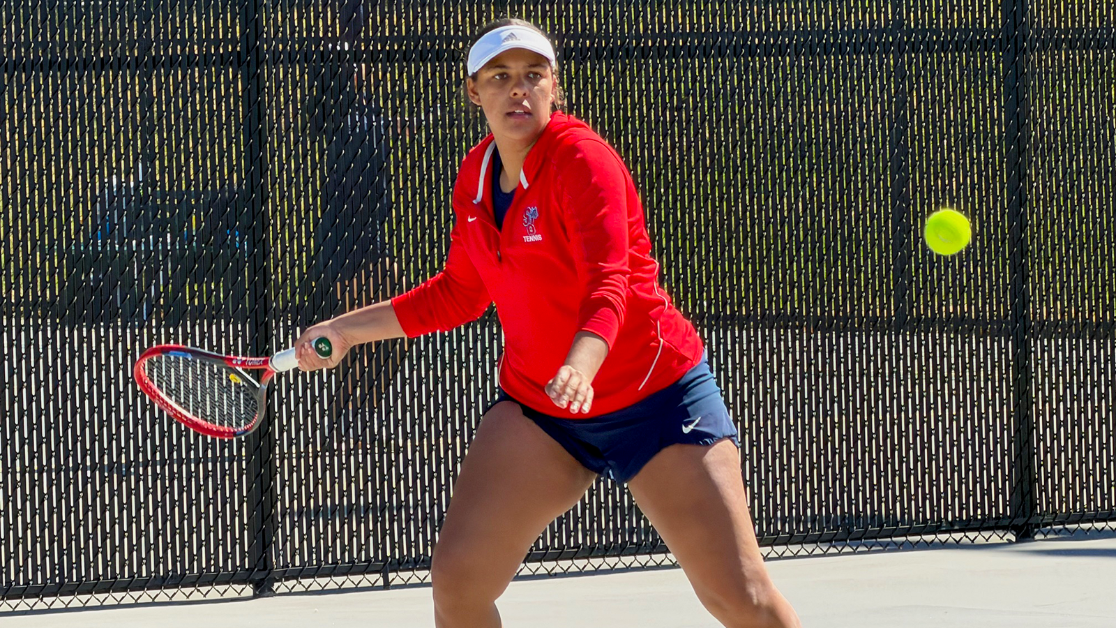 Paisha Douglas of Stony Brook prepares to return a shot on an outdoor tennis court, focused on the incoming ball with her racket ready.