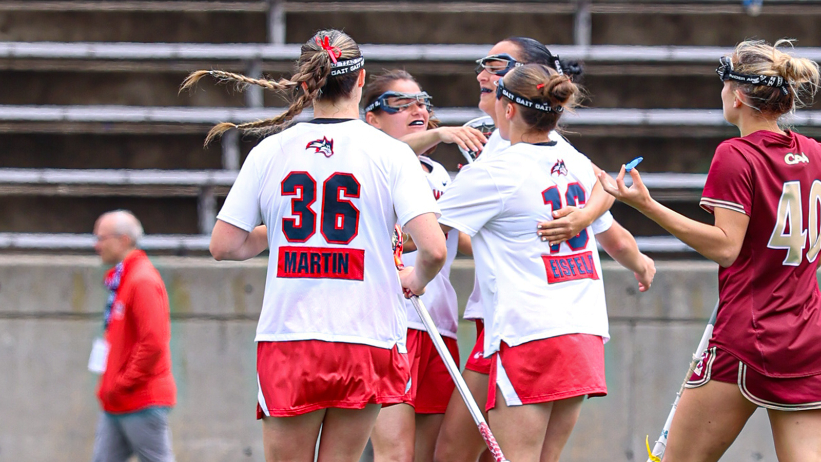 Stony Brook women's lacrosse players celebrate in a huddle following a goal. 