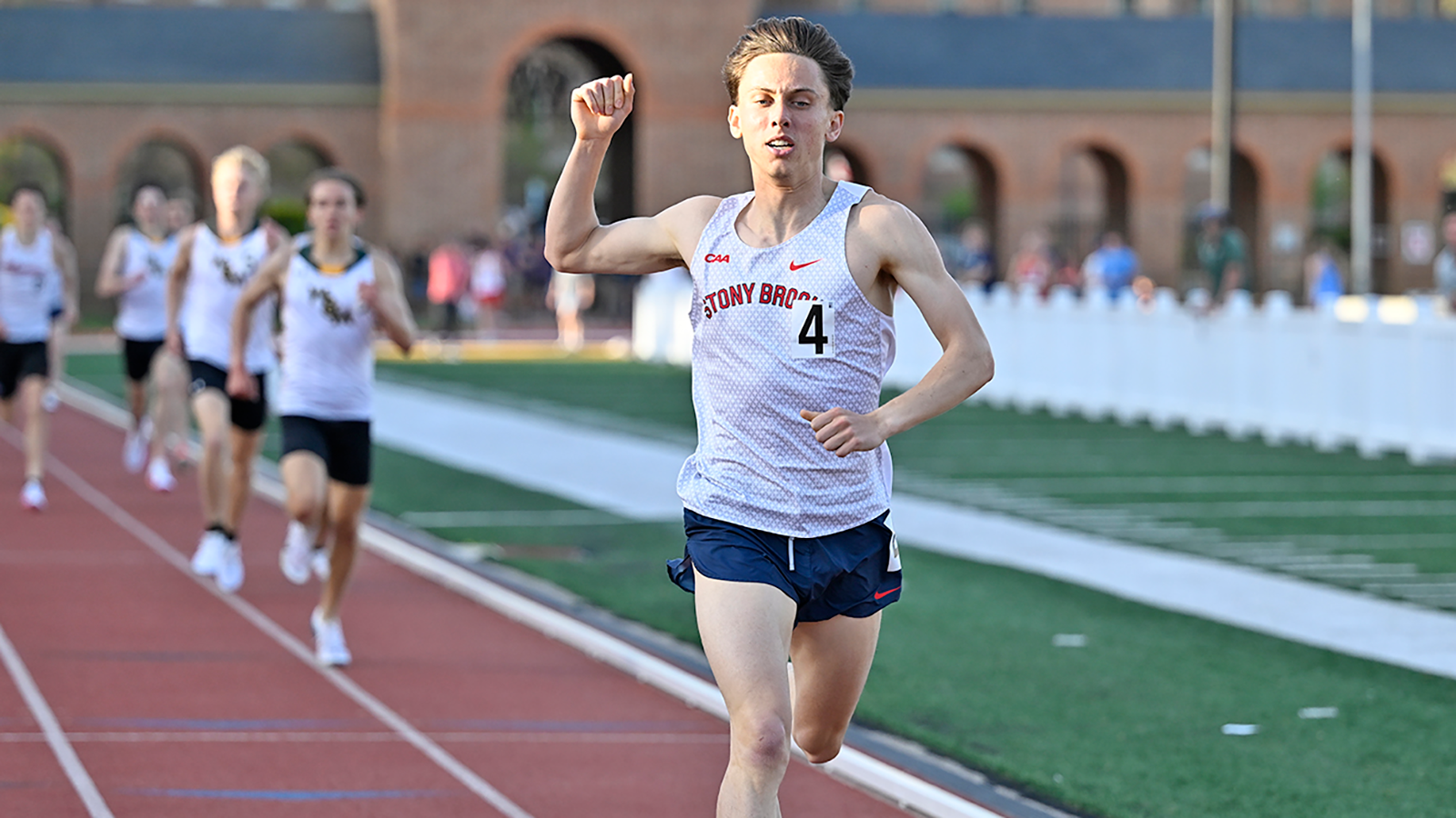 Stony Brook men's track & field athlete Caleb Gartner crossing the finish line with several runners behind him.