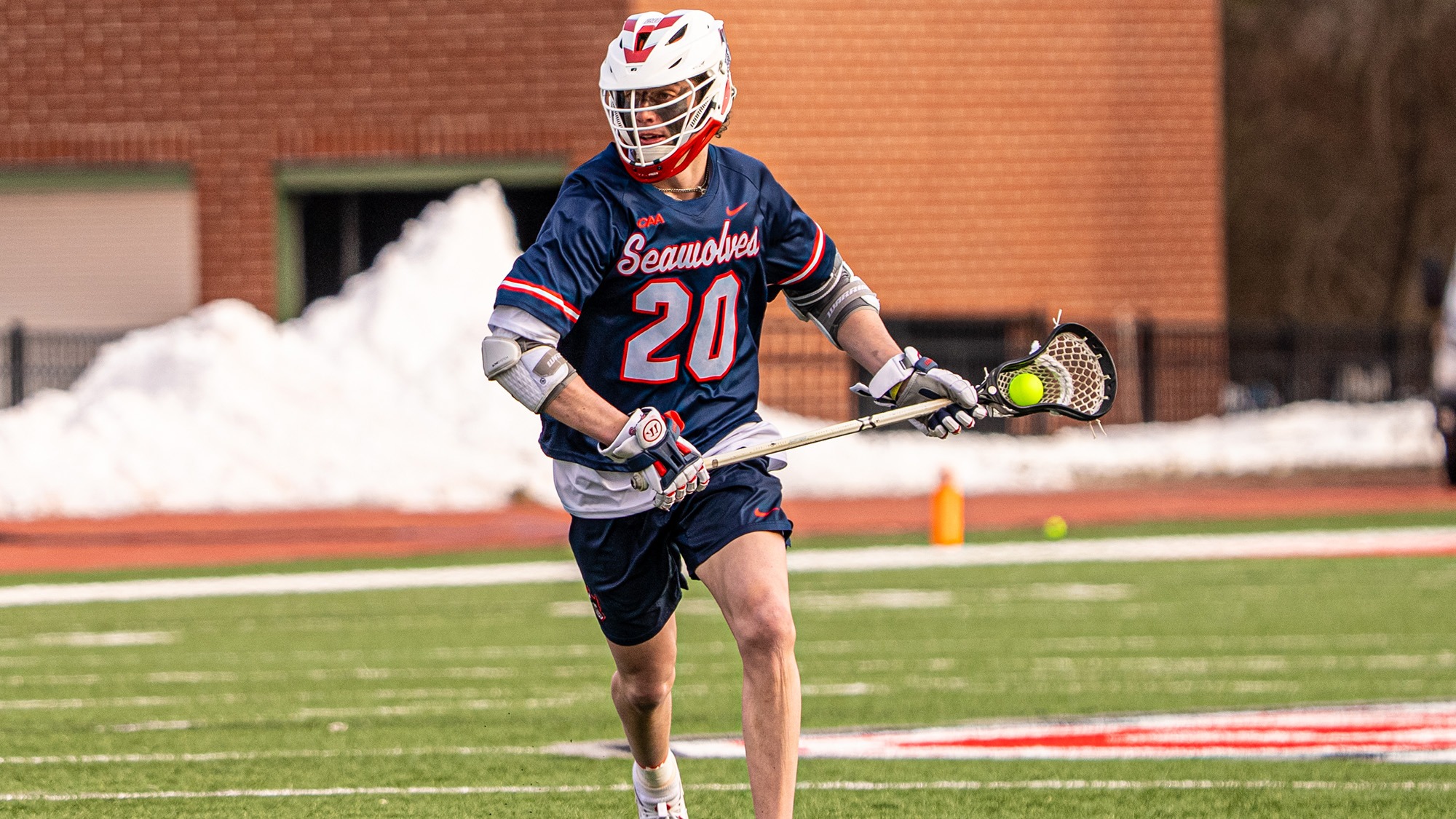 Stony Brook men's lacrosse player Jack Cavalieri in a navy Seawolves jersey cradles a lacrosse ball with his stick during game action.