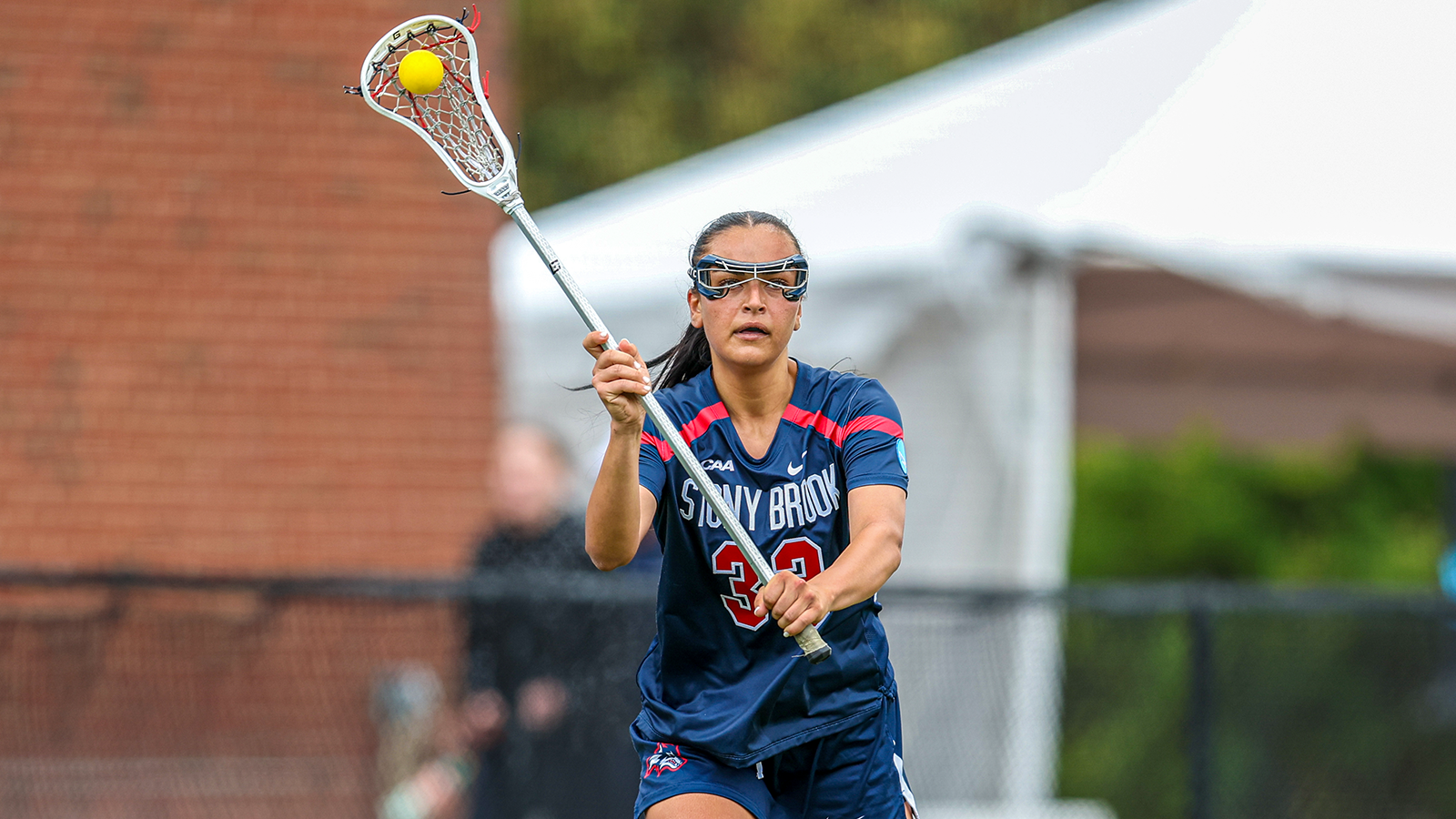 Mirabella Altebrando carrying the ball upfield with a lacrosse stick in her hands. 