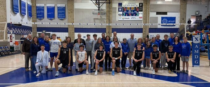 Senior Volleyball Bombers kneel with each other following win on Senior night over Crusaders 