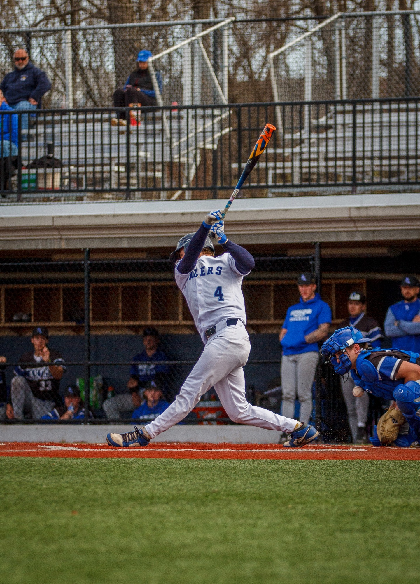Baseball player in white uniform swings a bat during a game.