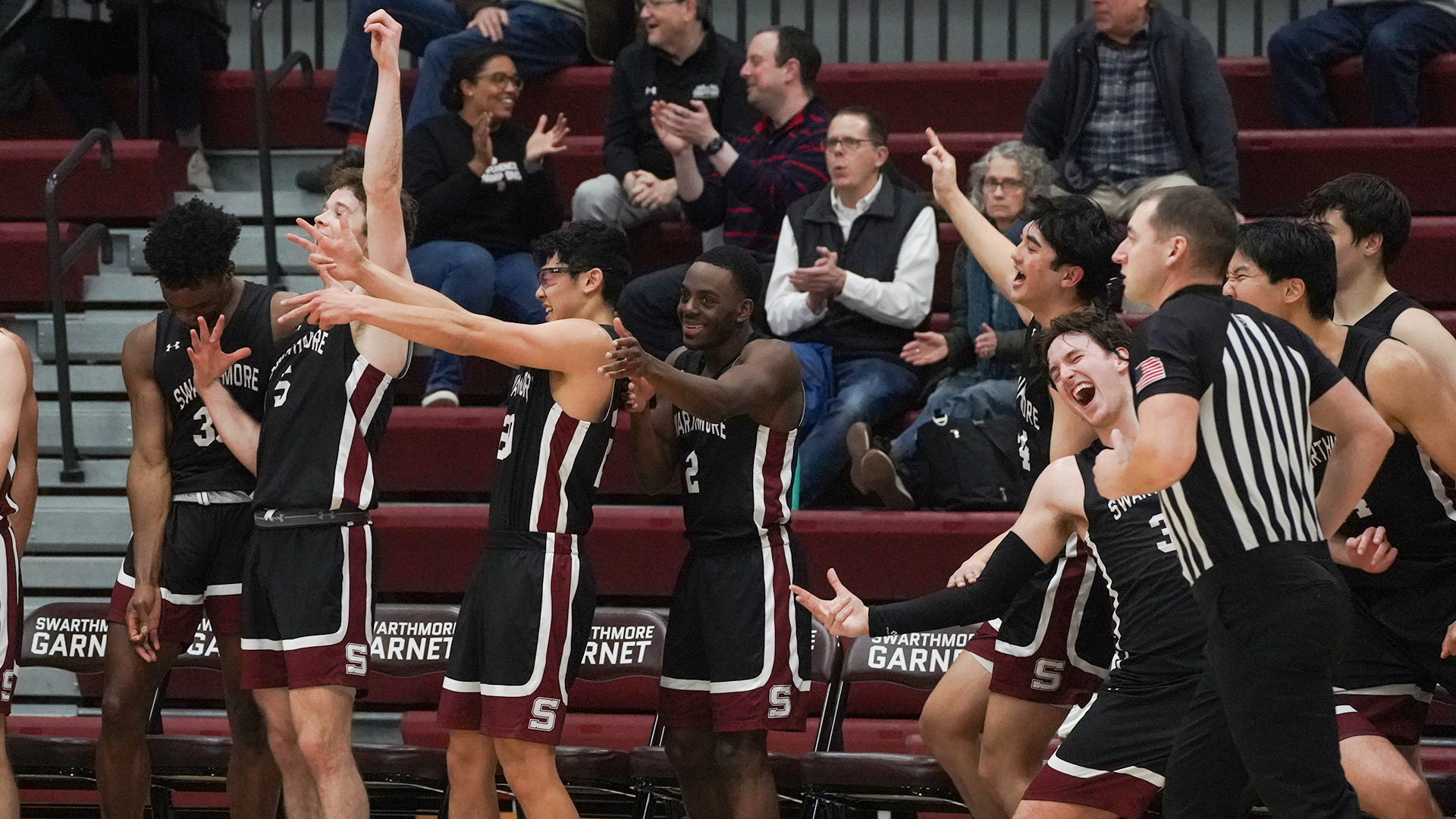 Men's basketball bench celebrates three