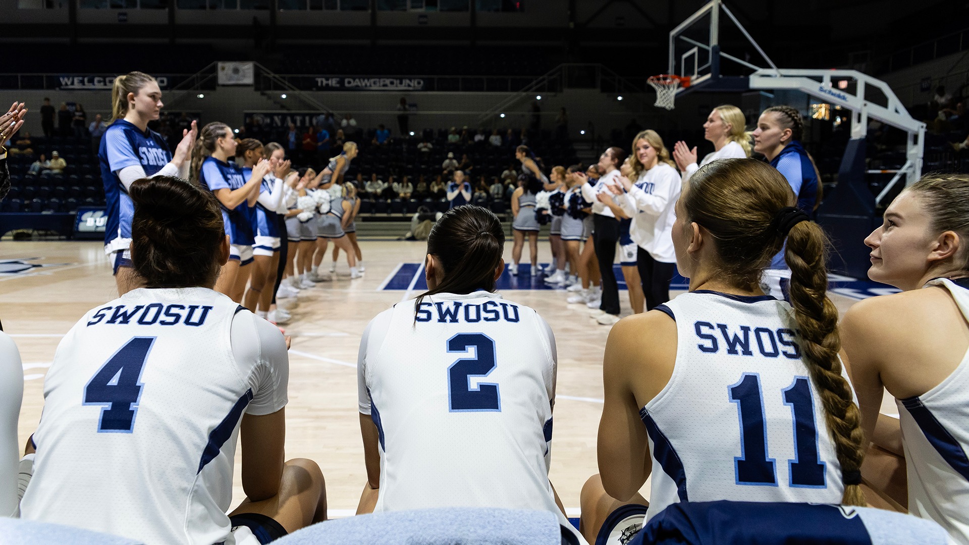 women's basketball starting lineup sits on the bench awaiting the starting lineups to be called