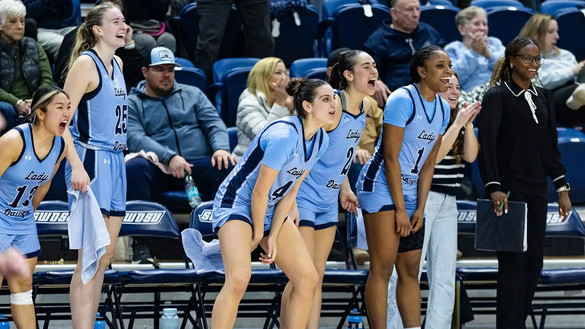 women's basketball bench celebrates teammates on the court
