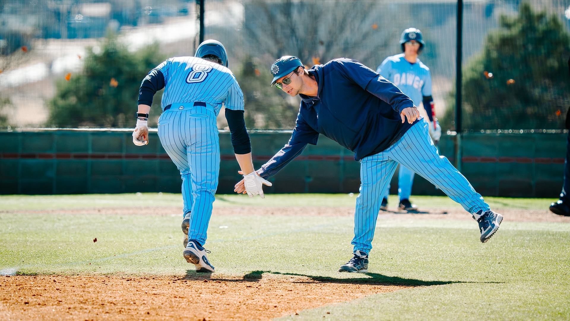 third base coach matt marlow gives base runners a high five after a home run
