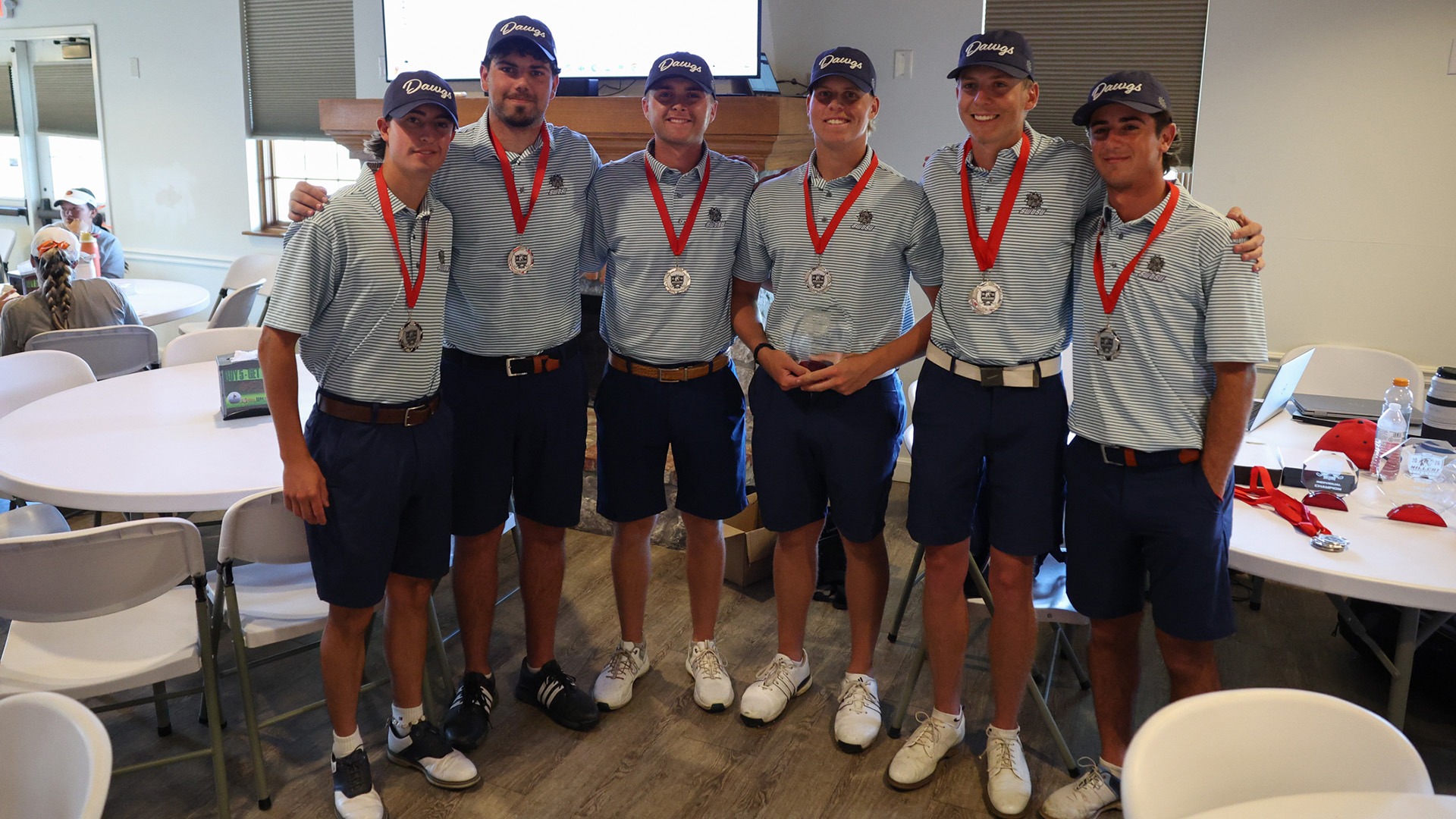 men's golf takes a team shot in the clubhouse after their win at the Hillcat Classic