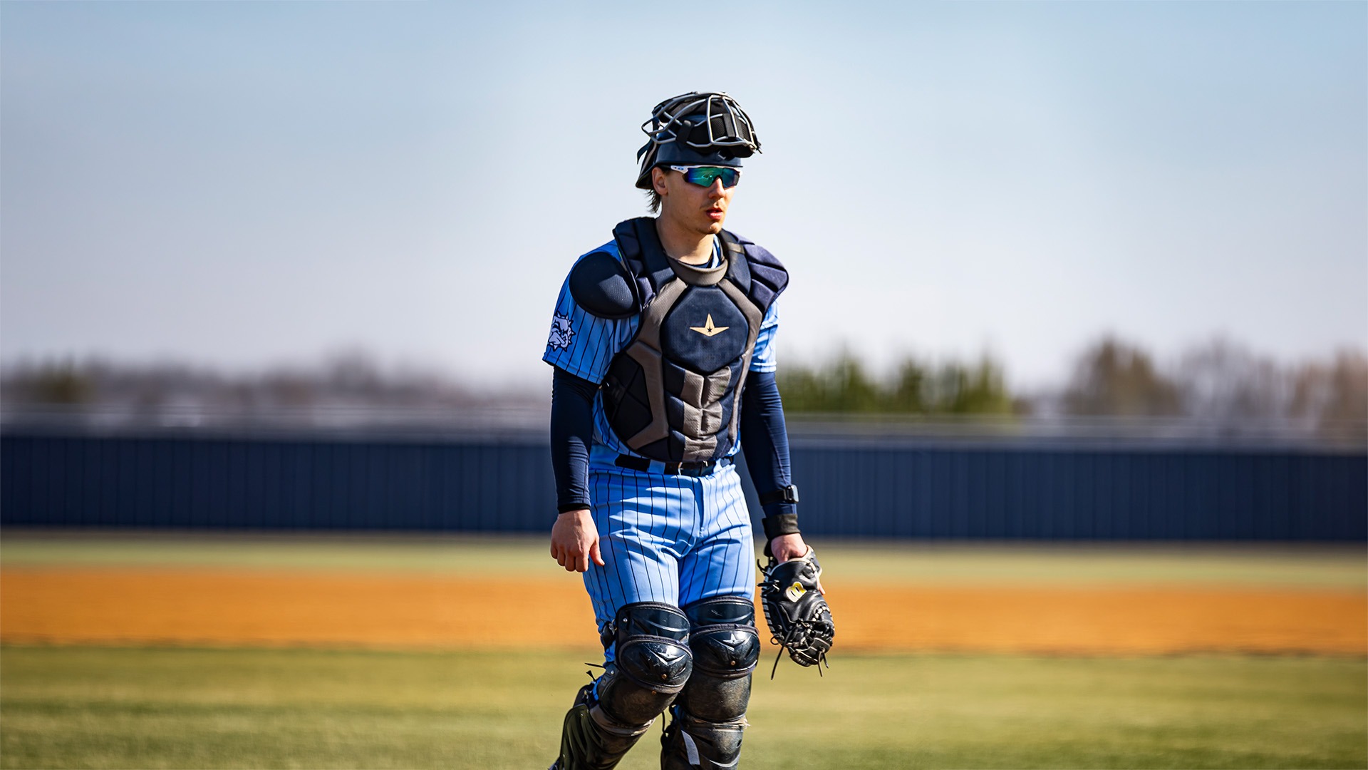 rusty wortman stands on the field in his catcher's gear