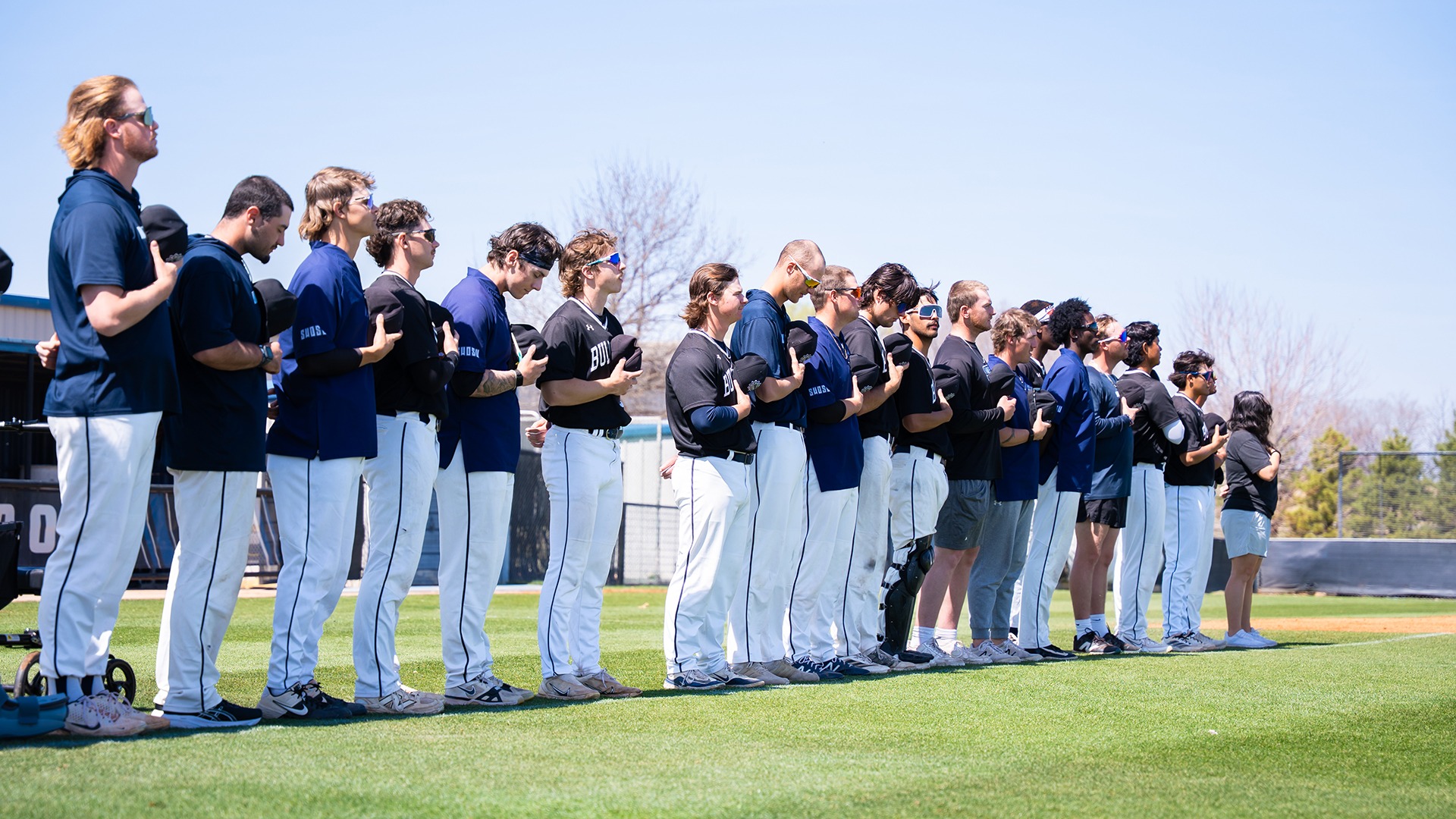 swosu baseball stands at the foul line during national anthem