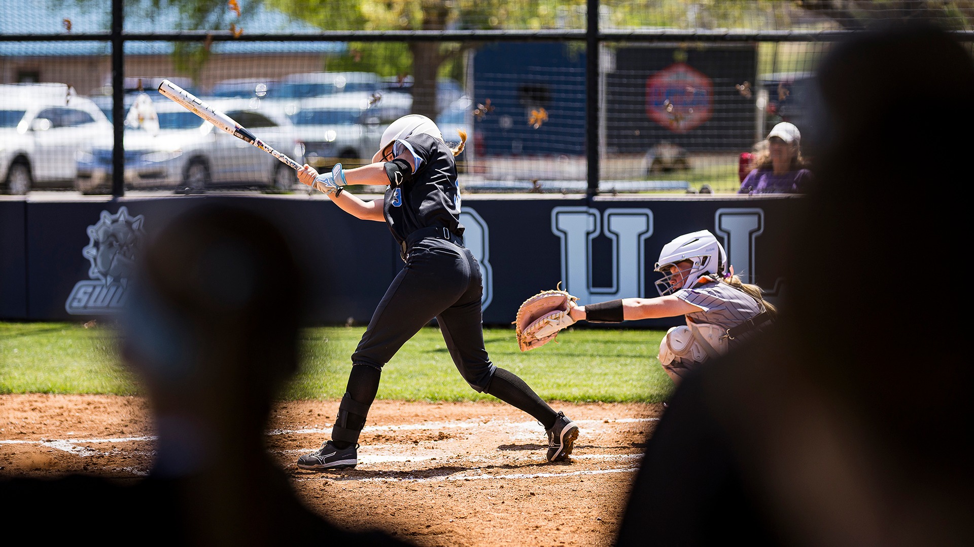 maddie rahon swings at a pitch wearing a black uniform