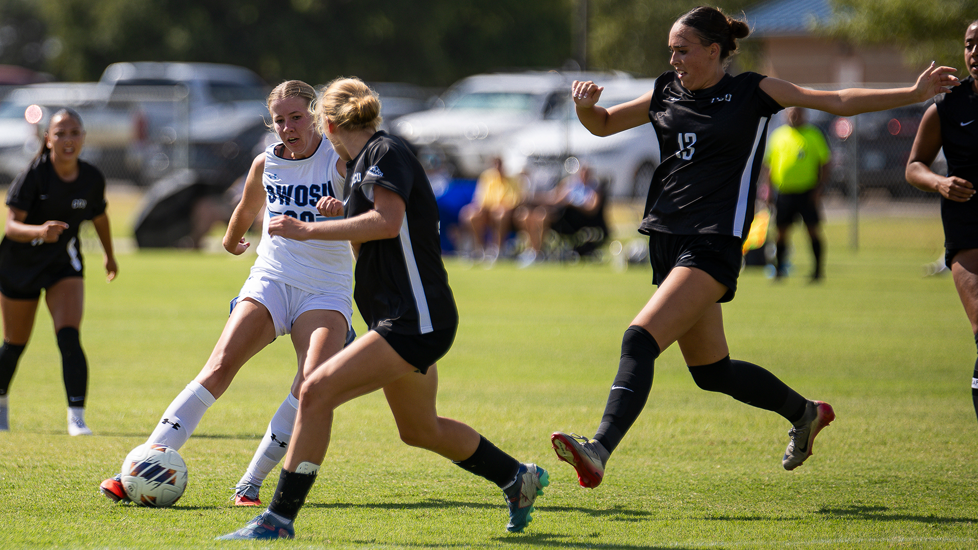 Krysta Hook dribbles a ball between CCU defenders