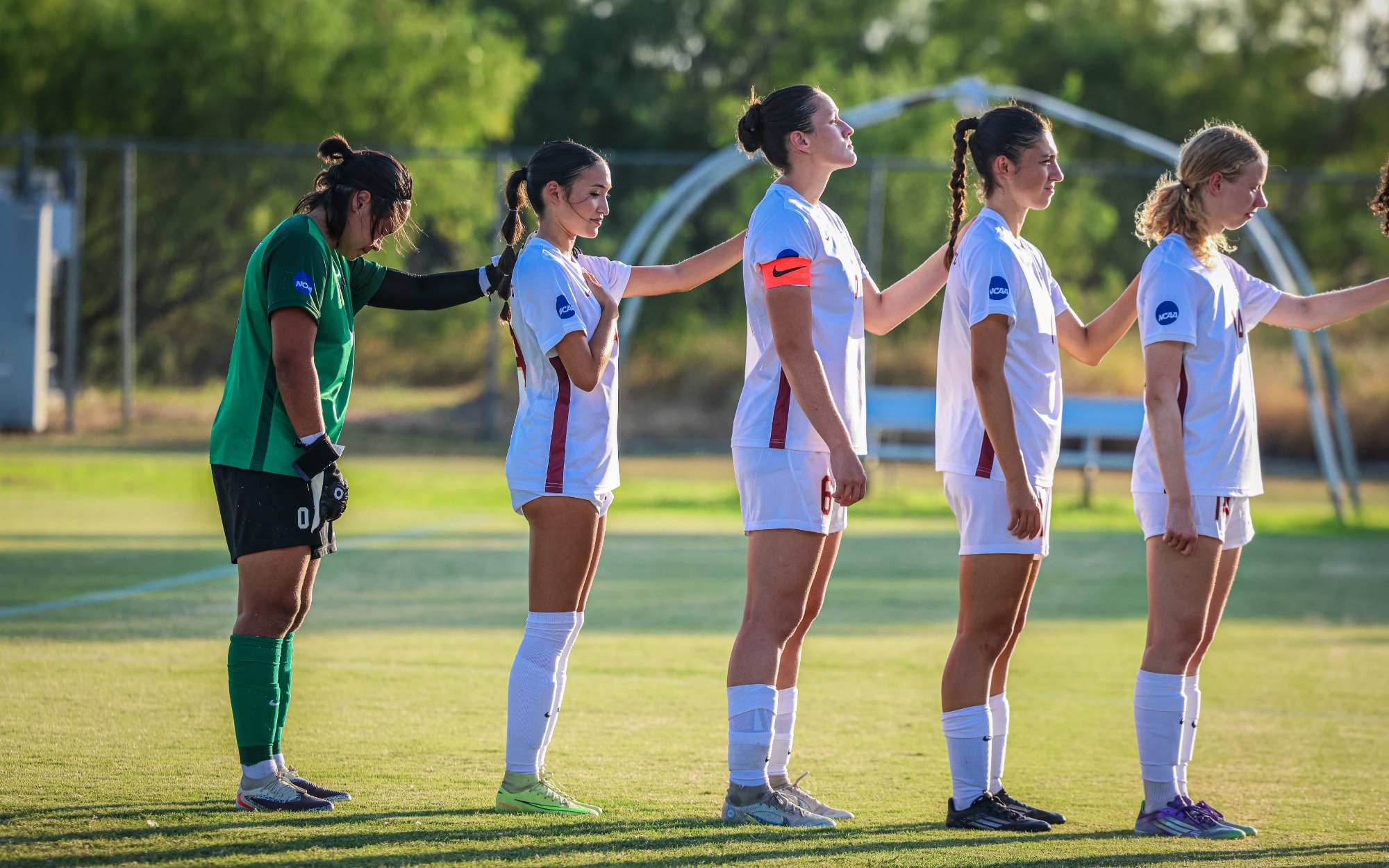 Starting line-up with hands on each other's shoulders for the National Anthem. 