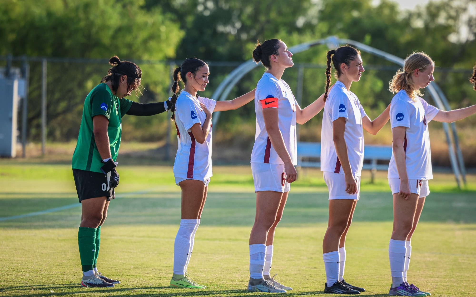Starting line-up with hands on each other's shoulders for the National Anthem. 