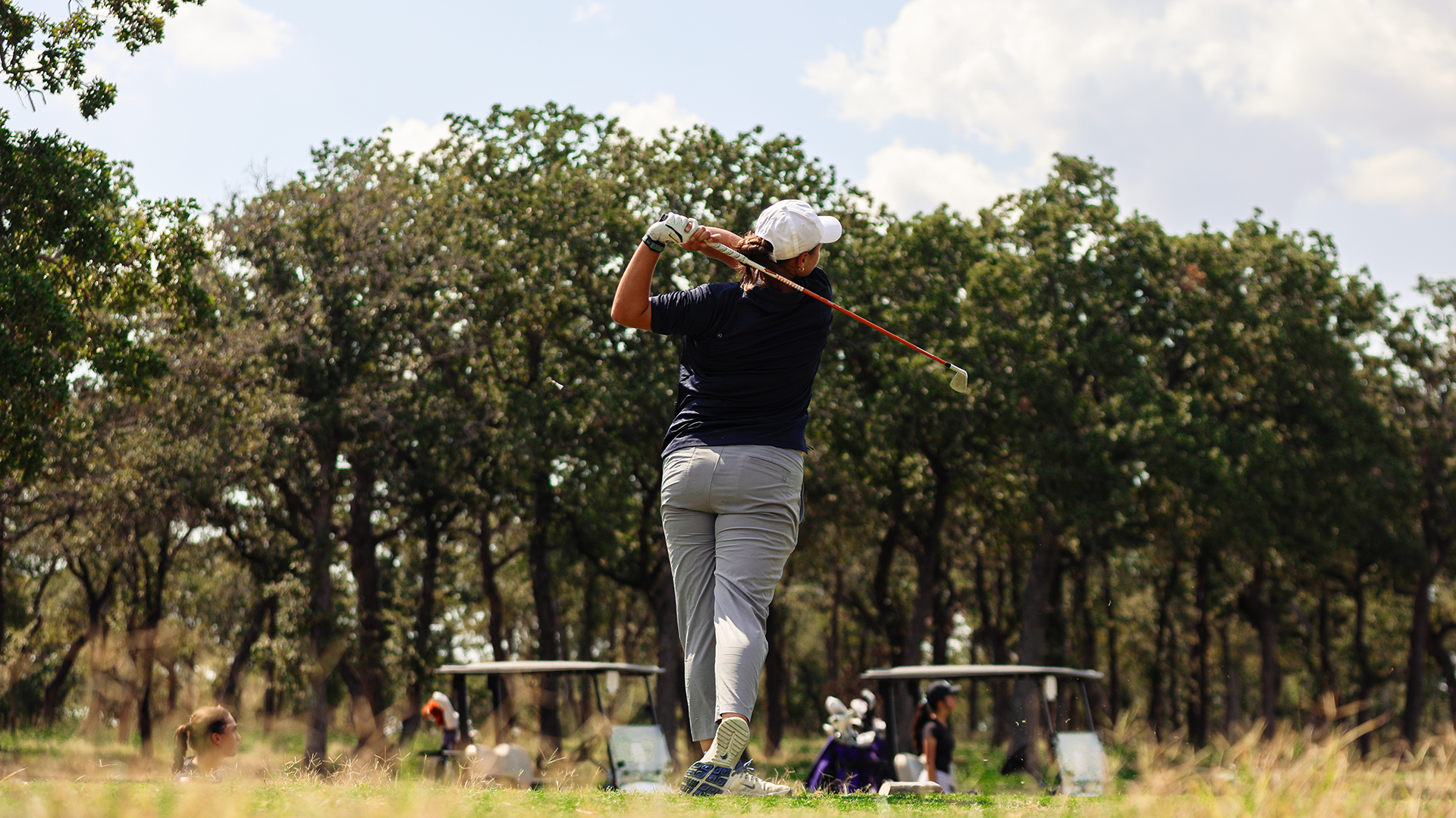 Louise Depadt teeing off in front of trees
